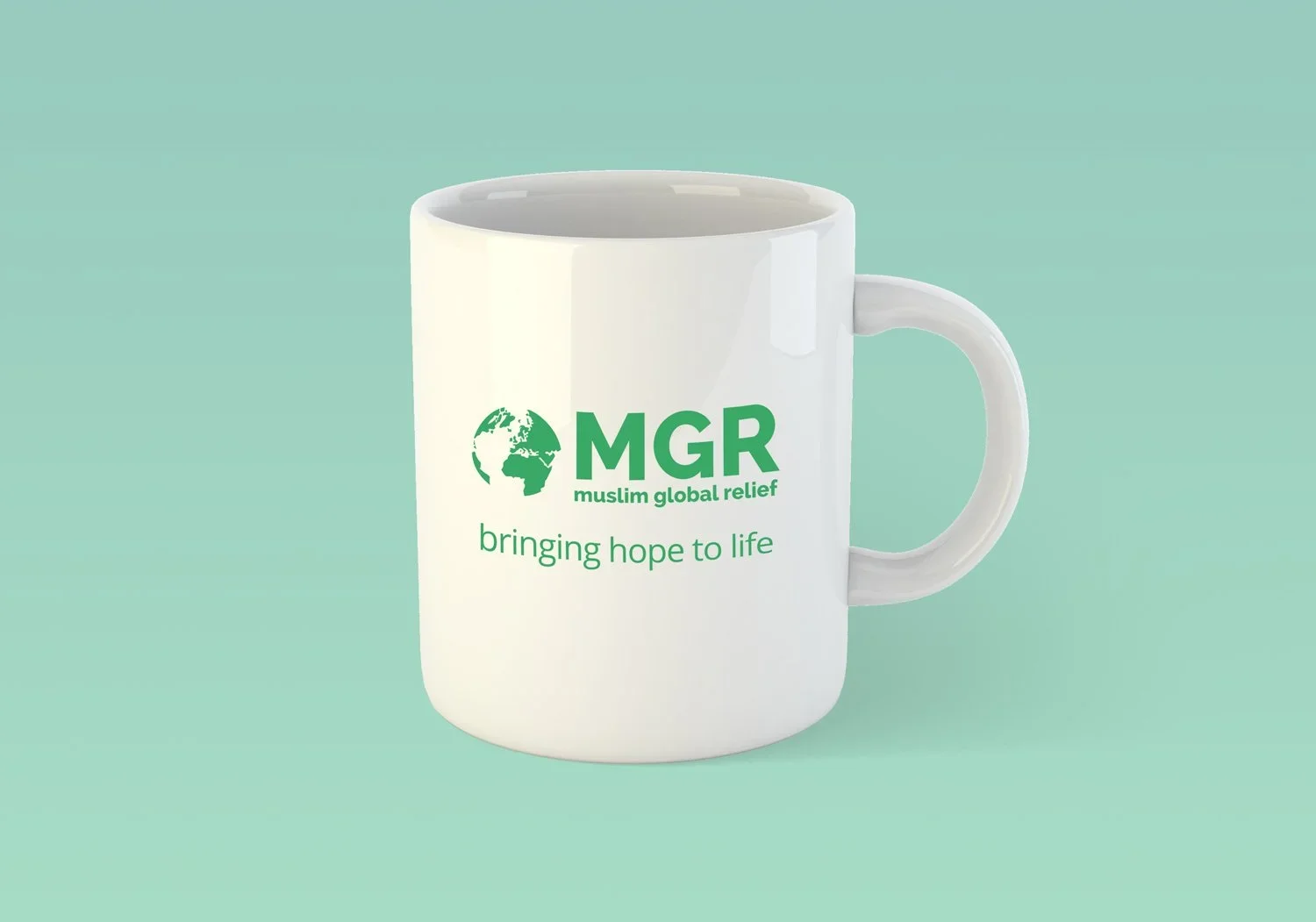 White ceramic mug with green logo and text that says 'MGR Muslim Global Relief bringing hope to life' against a light teal background.