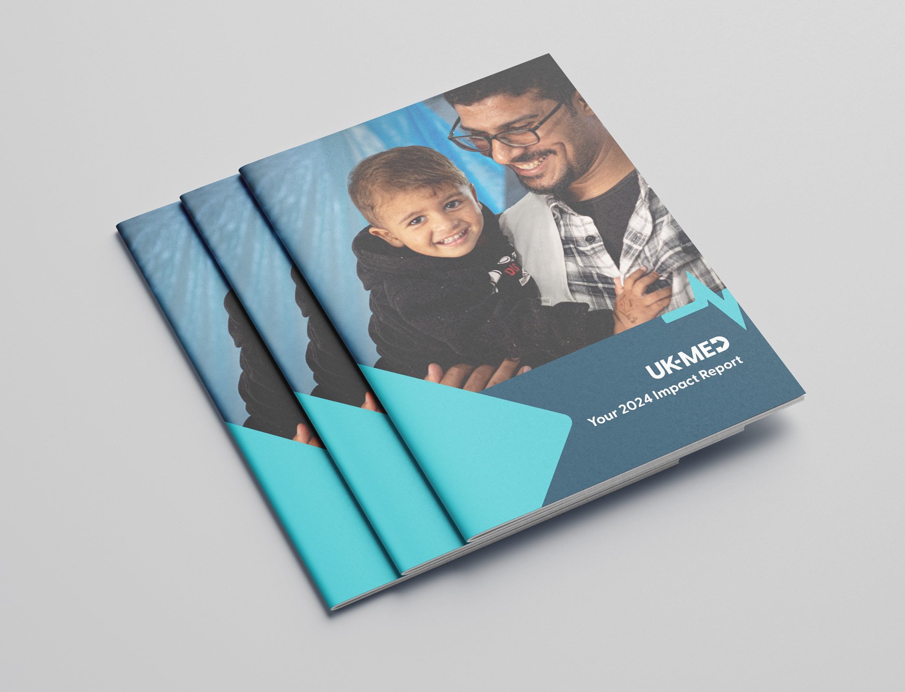 Three copies of a report titled "UK-MED Your 2024 Impact Report" with a cover photo of a smiling adult man holding a young boy, both smiling, against a blue background.