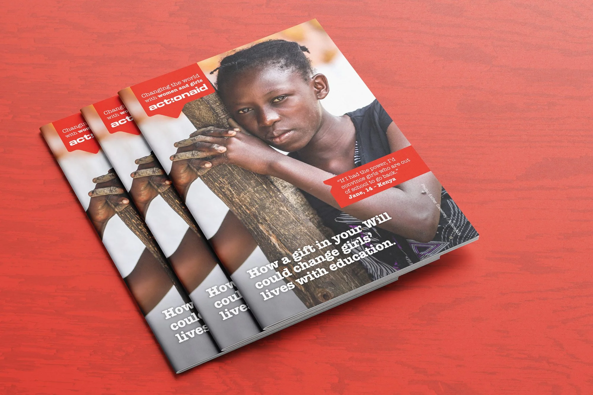 A magazine on a red wooden surface featuring a young girl resting her head and arms on a tree trunk. The magazine covers topics related to empowering girls through education, with a headline that reads 'How a gift in your Will could change girls' liv