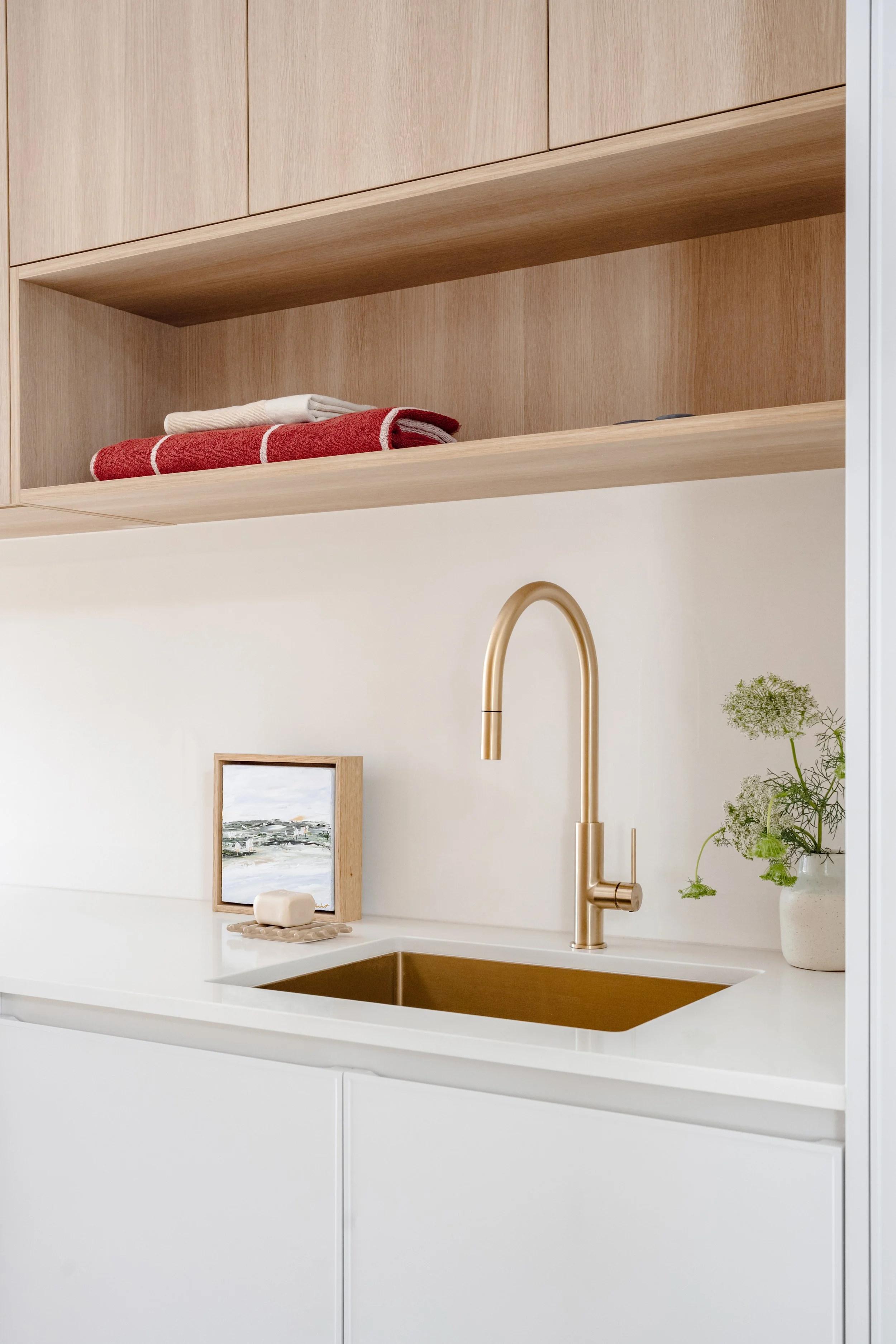 Fresh laundry colour palette with brass finishes. Warm natural oak paired with white base cabinetry and stone benchtops