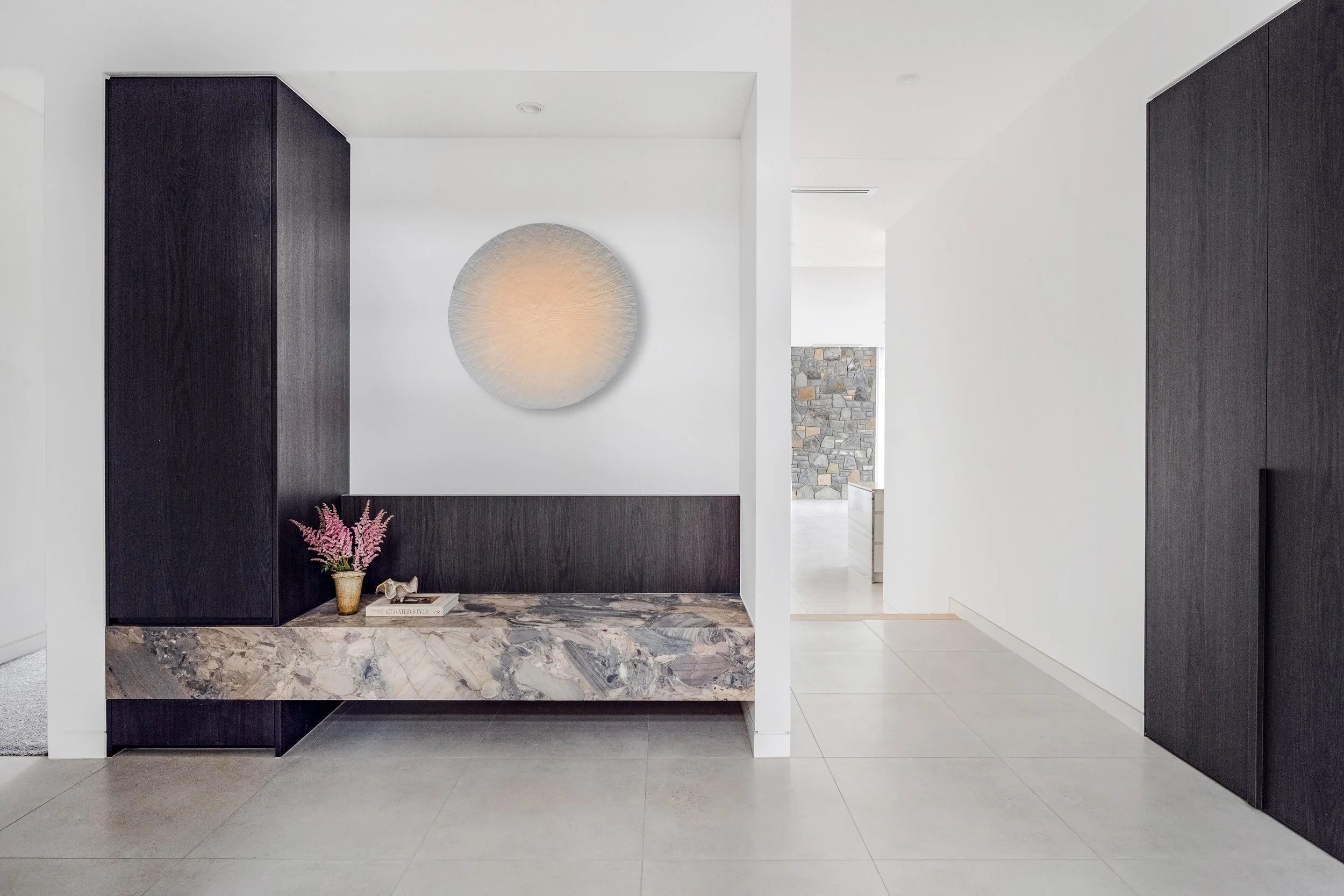 A beautiful entry way joinery with natural marble features paired with deep timber cabinetry.
