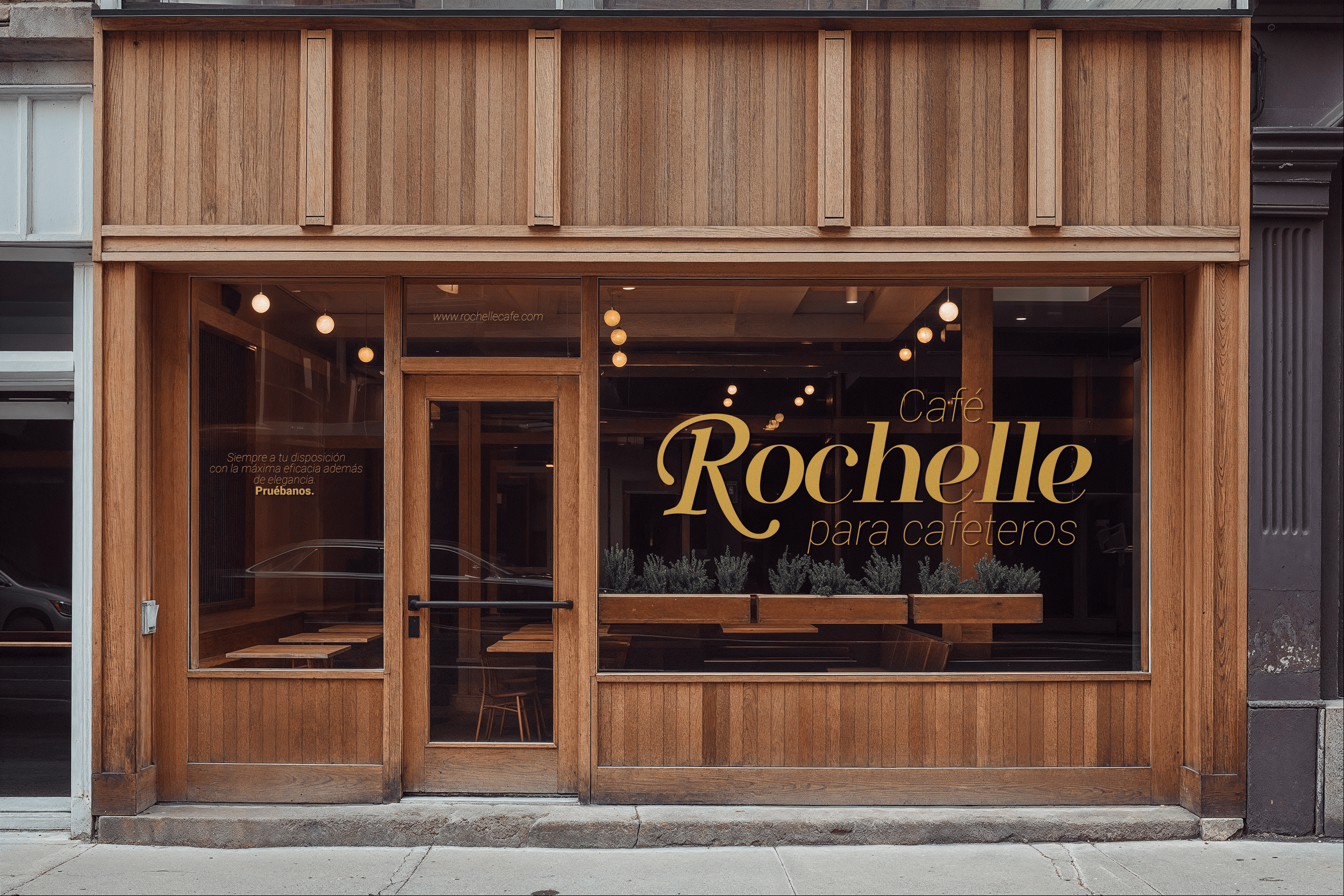Fachada de un café con grandes ventanales de vidrio y estructura de madera, con el letrero 'Café Rochelle para cafetoros' en la ventana.