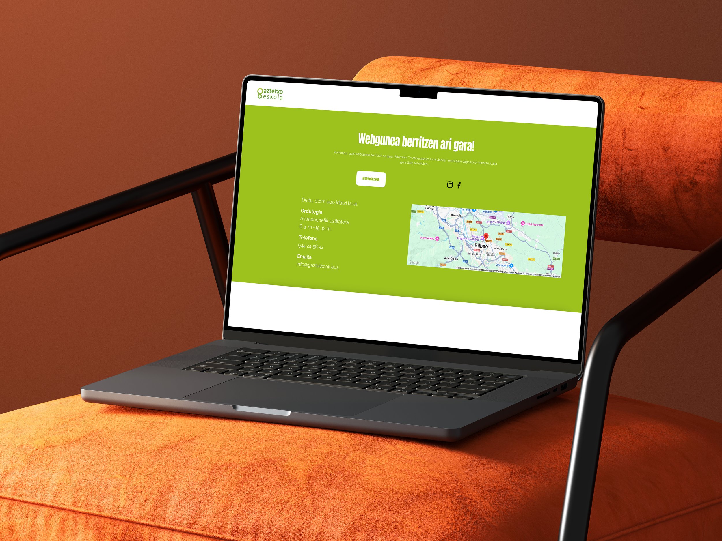 Pantalla de computadora portátil con página web en color verde, mostrando un mapa y datos de contacto, sobre un sillón naranja con estructura de metal negro.