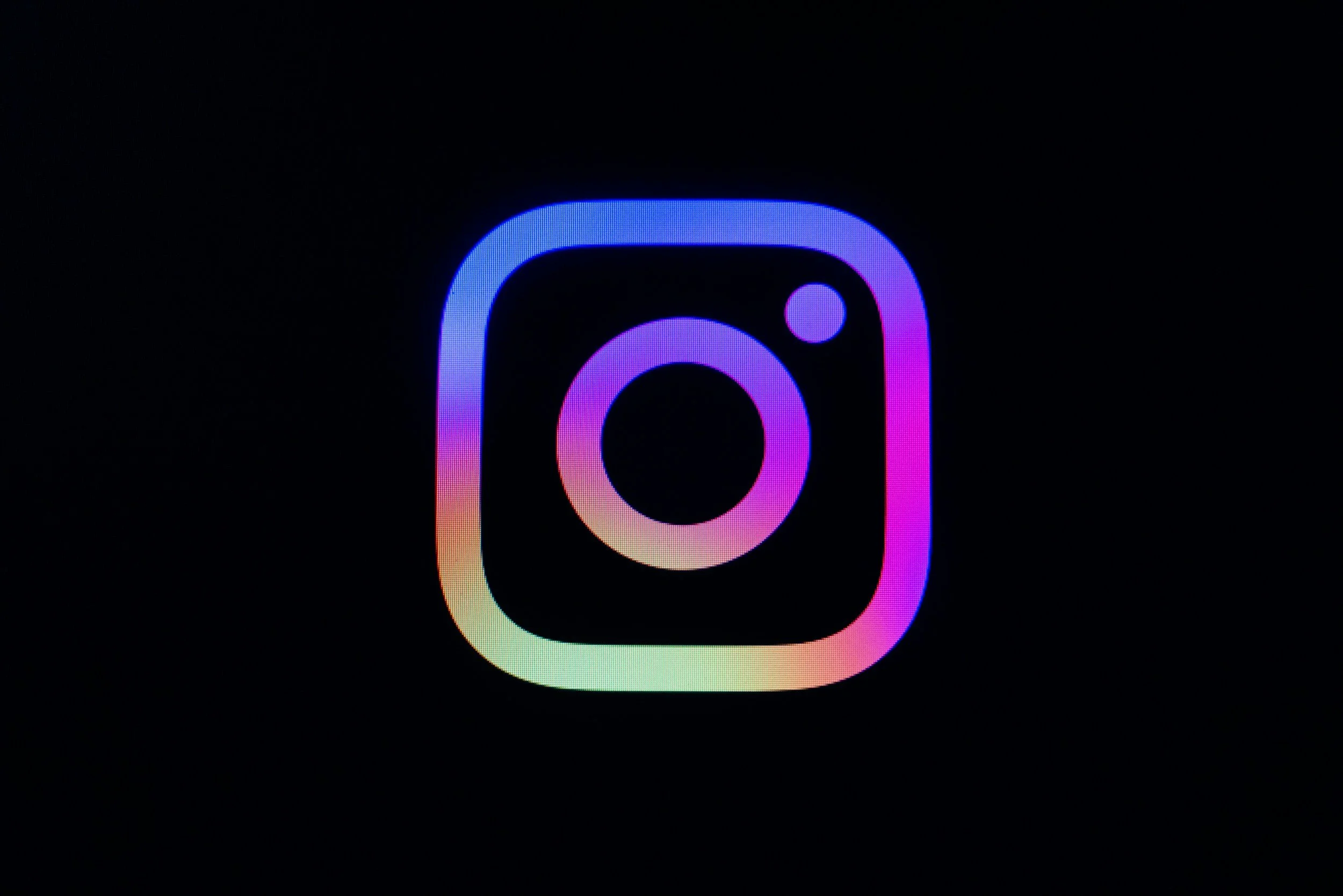 Instagram-Logo in Regenbogenfarben auf schwarzem Hintergrund.