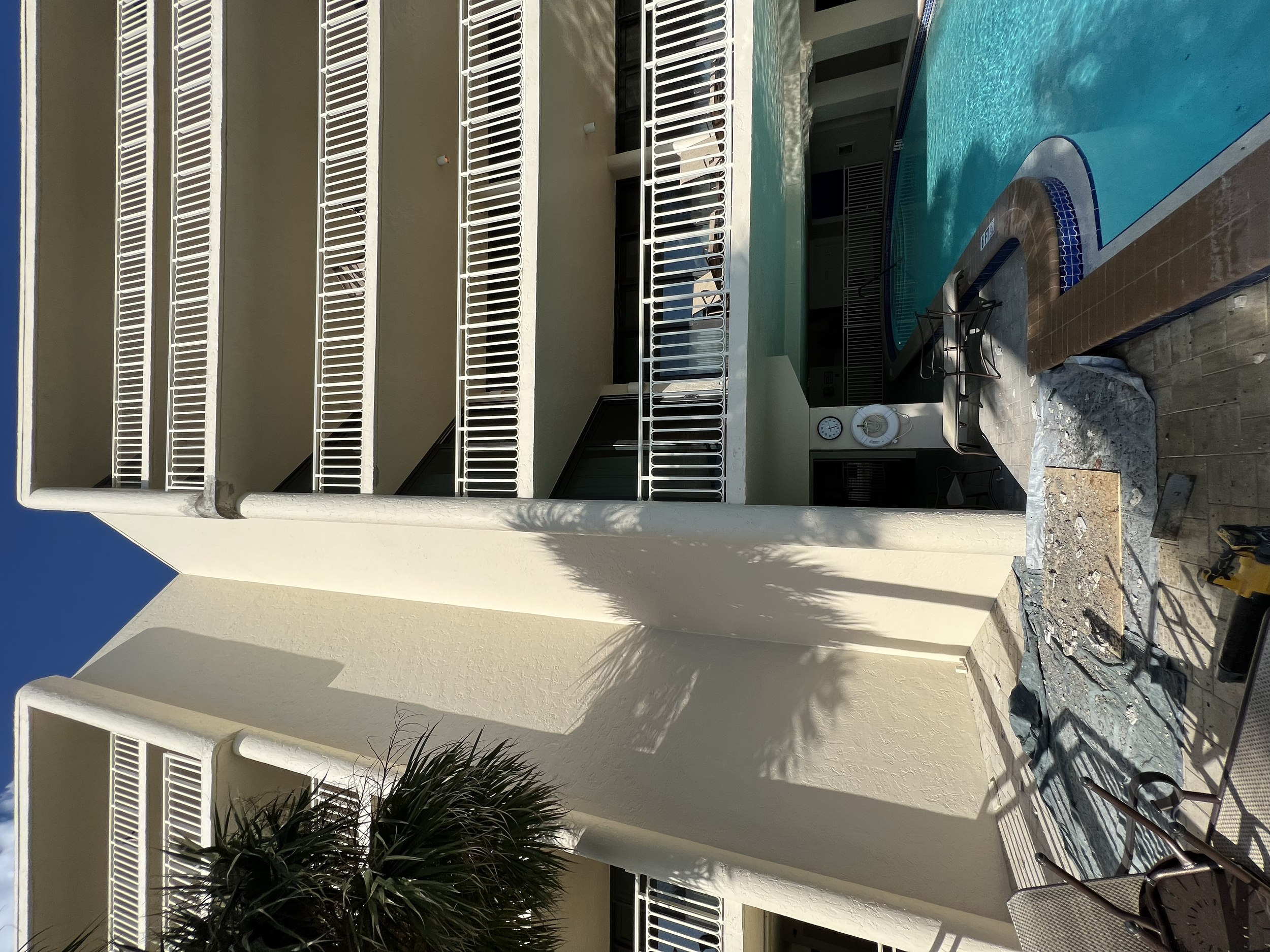 Construction work near a swimming pool with a partially torn wall and construction tools.
