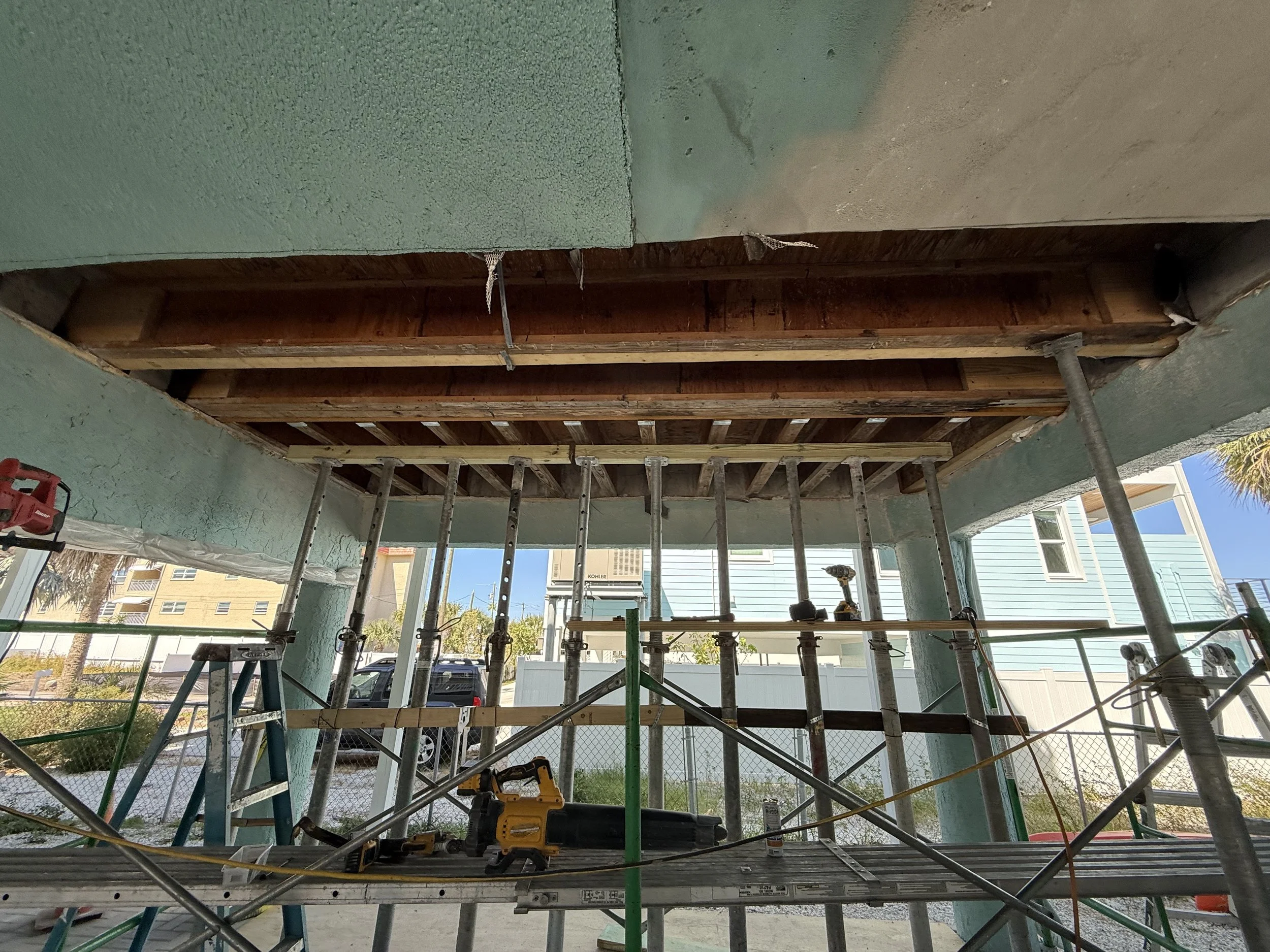 Construction site showing scaffolding, tools, and an unfinished ceiling with exposed wooden beams.