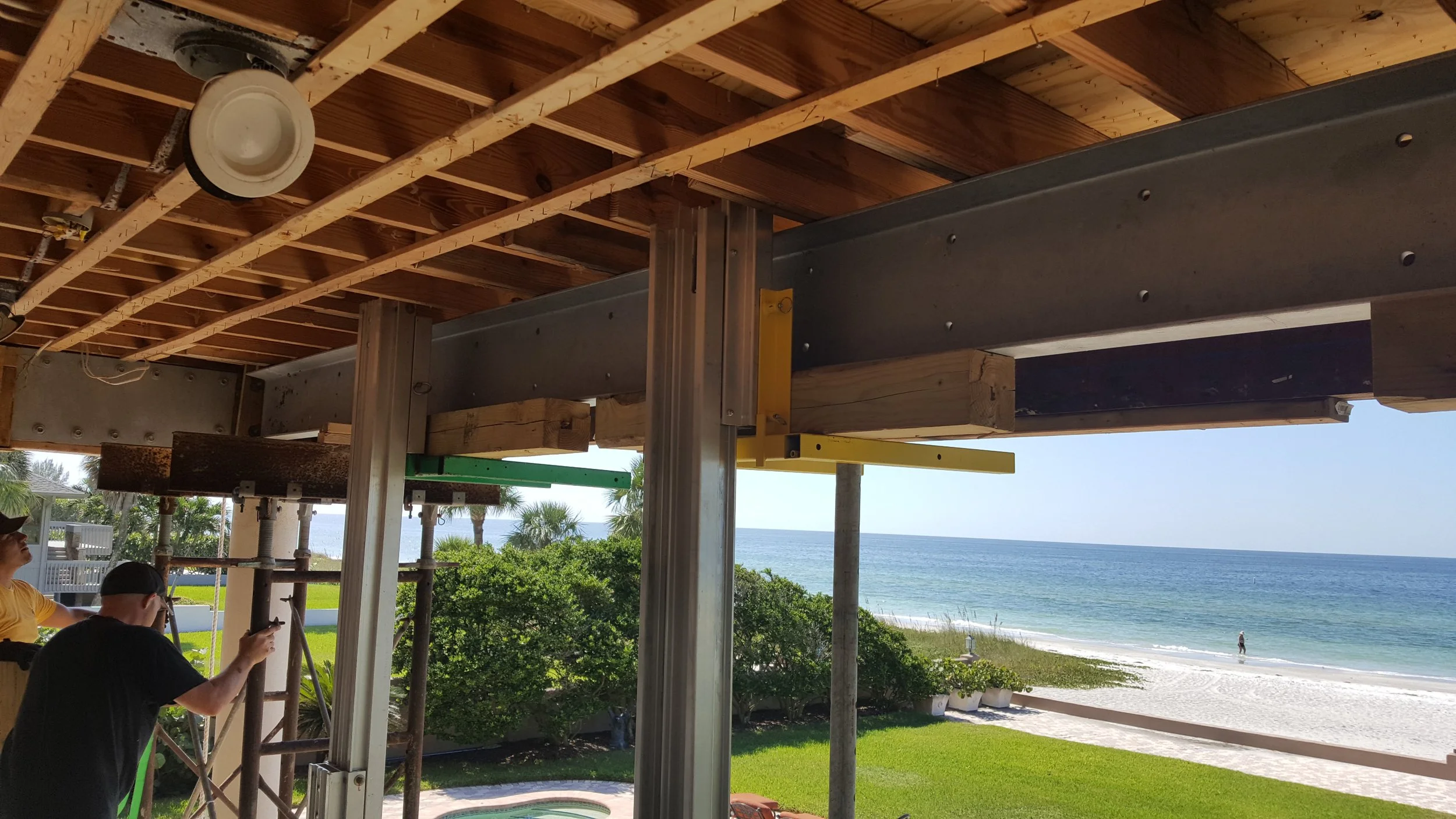 Construction workers building a house with a view of the beach and ocean in the background.