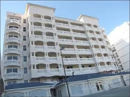 Multi-story white residential building with curved balconies and glass windows in an urban setting.