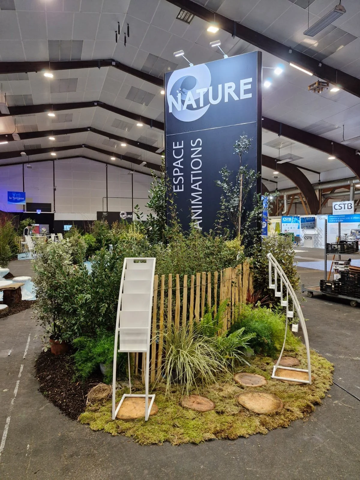Une section de l'exposition Nature dans un centre d'exposition, avec des plantes vertes et un panneau indiquant Espace Animations.
