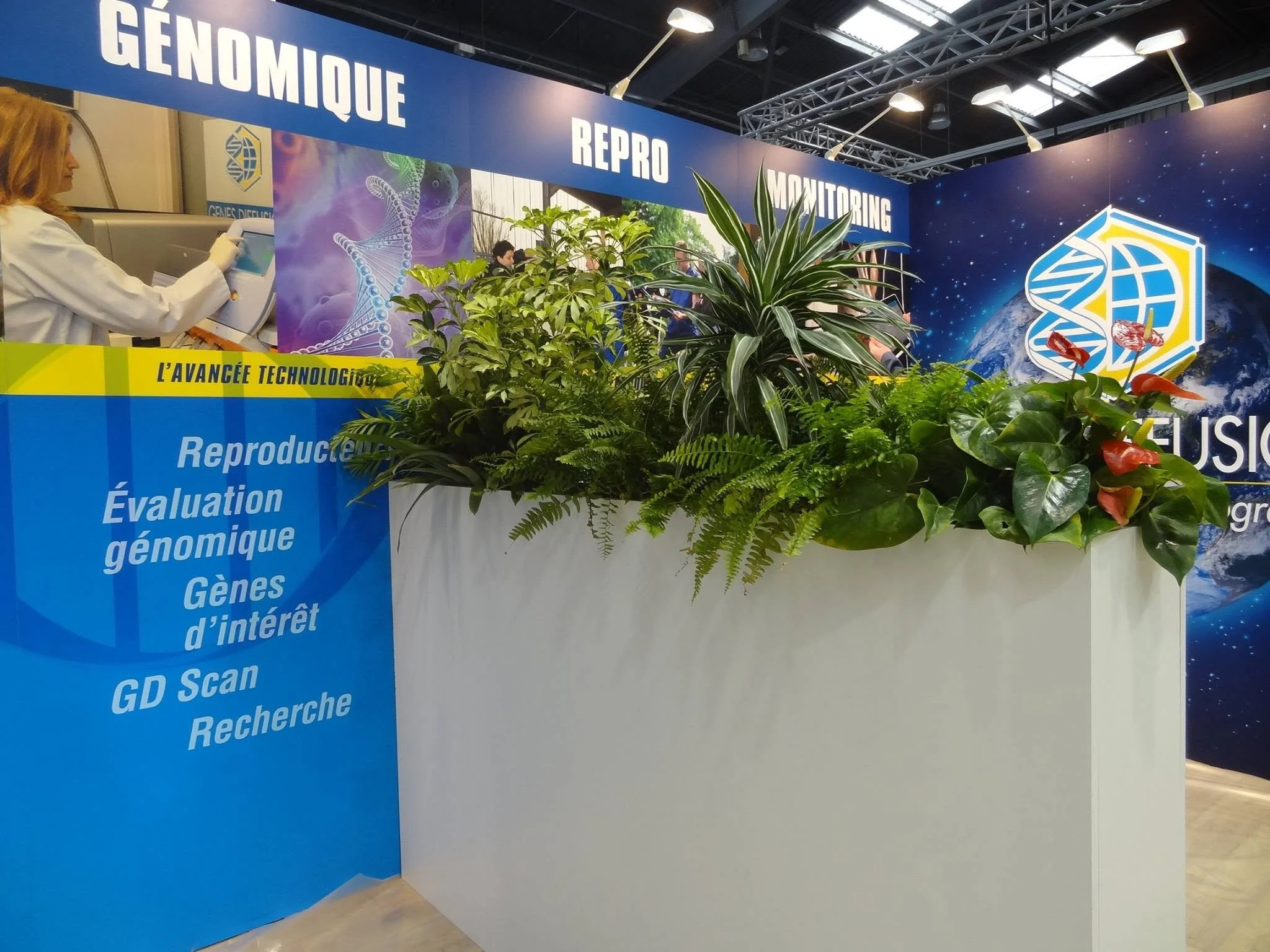 Une affiche d'exposition avec des mots en français comme « génomique », « REPRO », « monitoring » et une bannière bleue avec des listes de services ou thèmes liés à la génomique, la recherche et la technologie, avec des plantes vertes en premier plan.