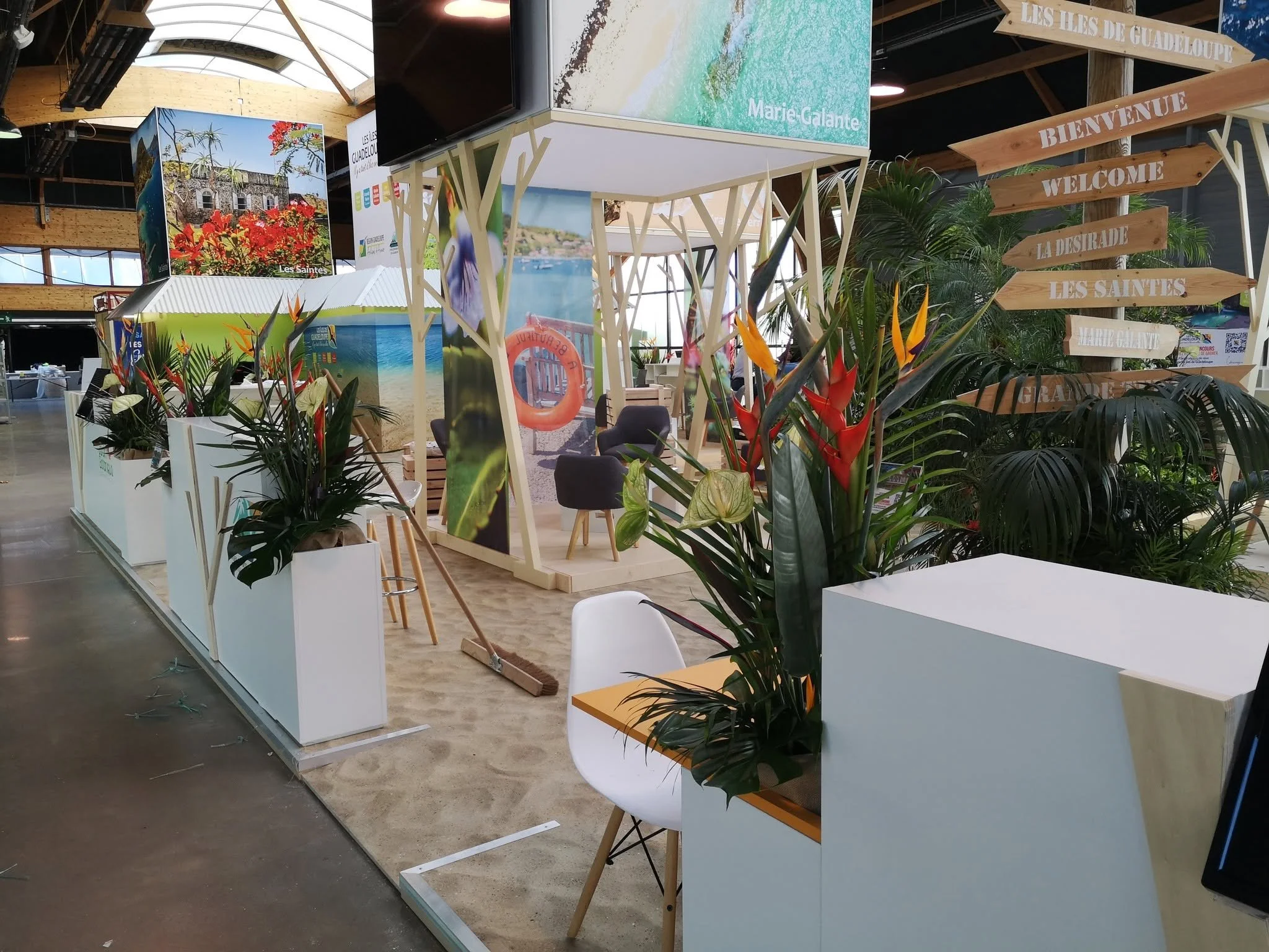 Un espace d'exposition avec des panneaux d'information, des plantes décoratives et des affiches illustrant des paysages et des endroits touristiques.