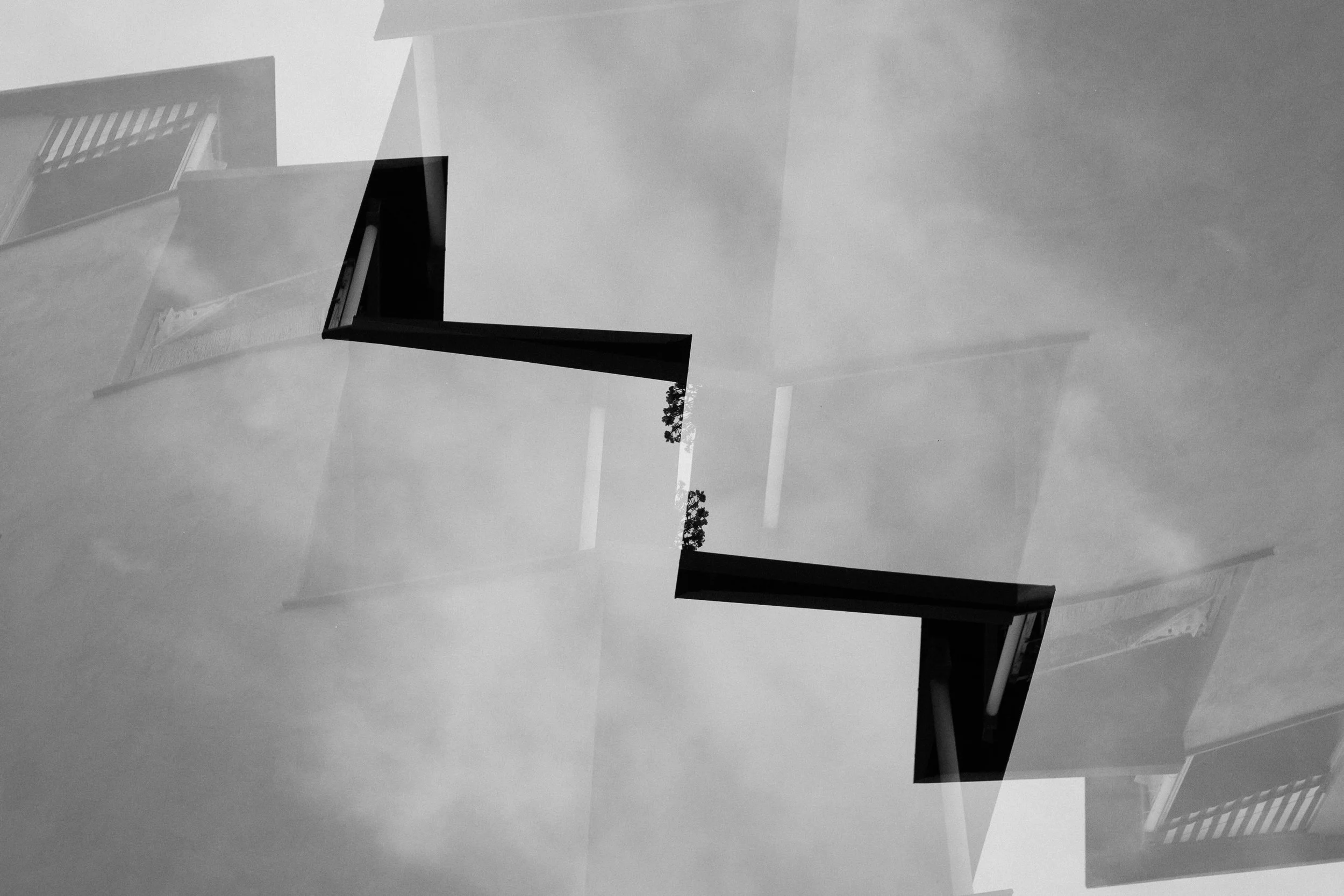 Foto in bianco e nero di un angolo di una stanza con una finestra, e alcune parti di muri e soffitto visibili.