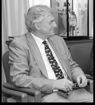 Portrait of Sir Robin Christopher seated during a meeting or discussion.