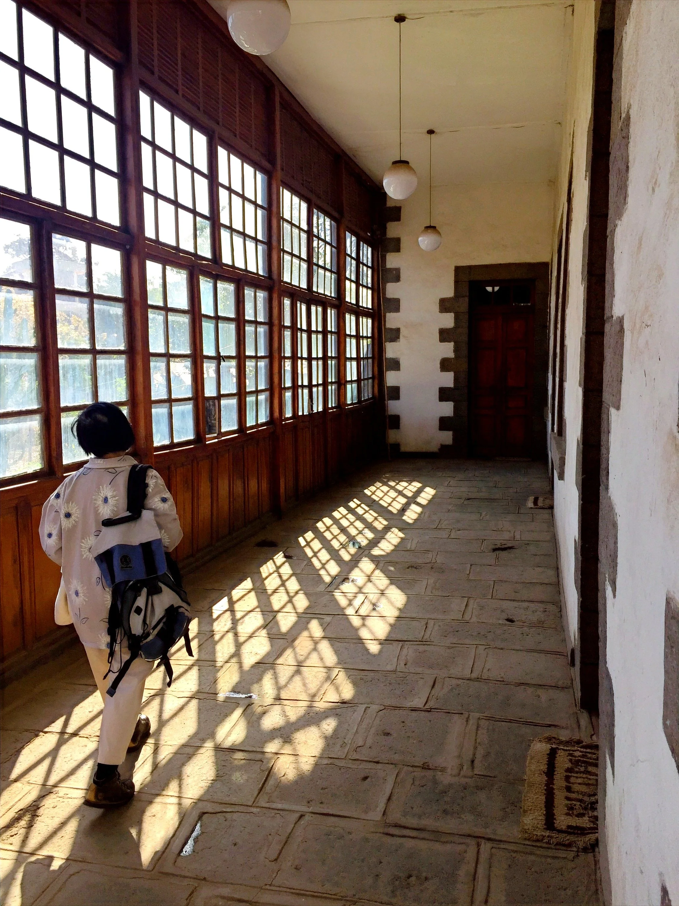 Interior corridor of the Ethiopian Heritage Trust headquarters in Addis Ababa, showing wooden windows, stone flooring and sunlight across the restored historic building.