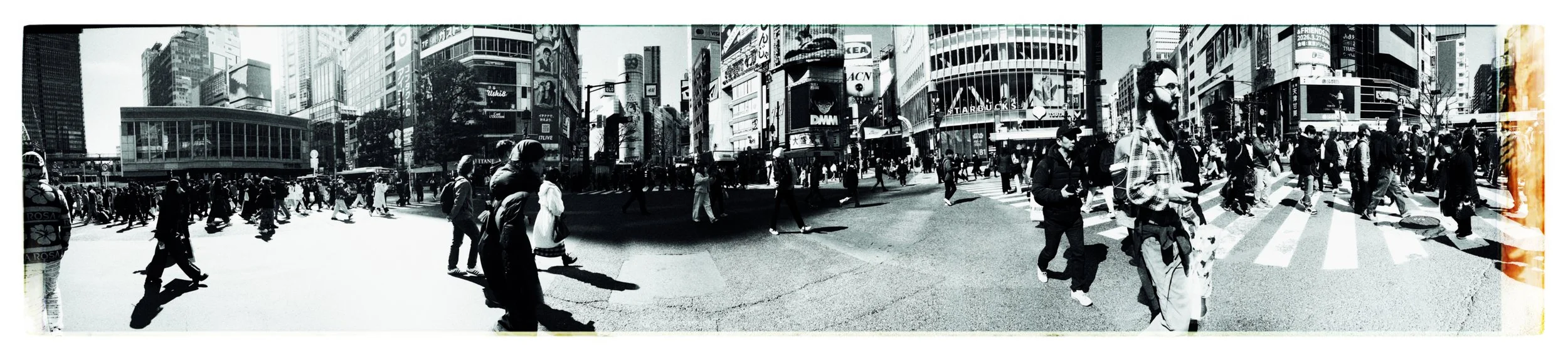 都市の交差点を多くの人々が横断歩道を渡っている黒と白の写真