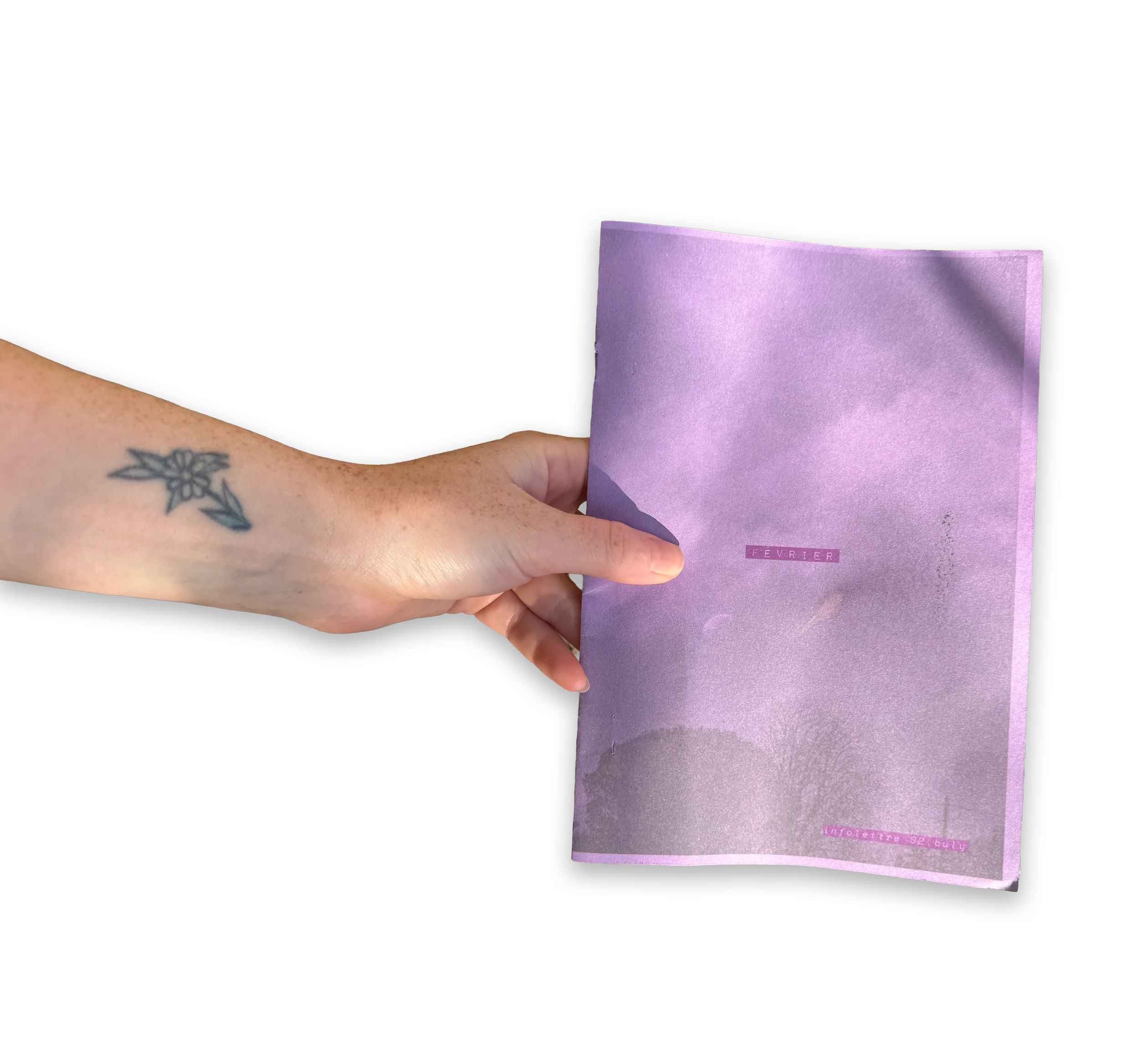 Une main tenant un programme ou une brochure violette avec le mot 'Février' écrit dessus, contre un fond noir.
