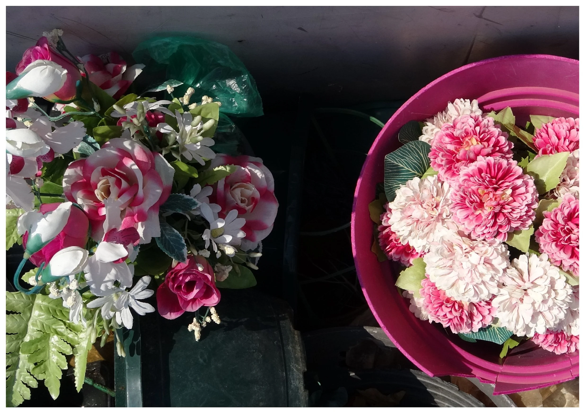 Deux bouquets de fleurs artificielles, l'un avec des roses et des petites fleurs blanches, l'autre avec des grandes fleurs roses et blanches dans un seau rose.