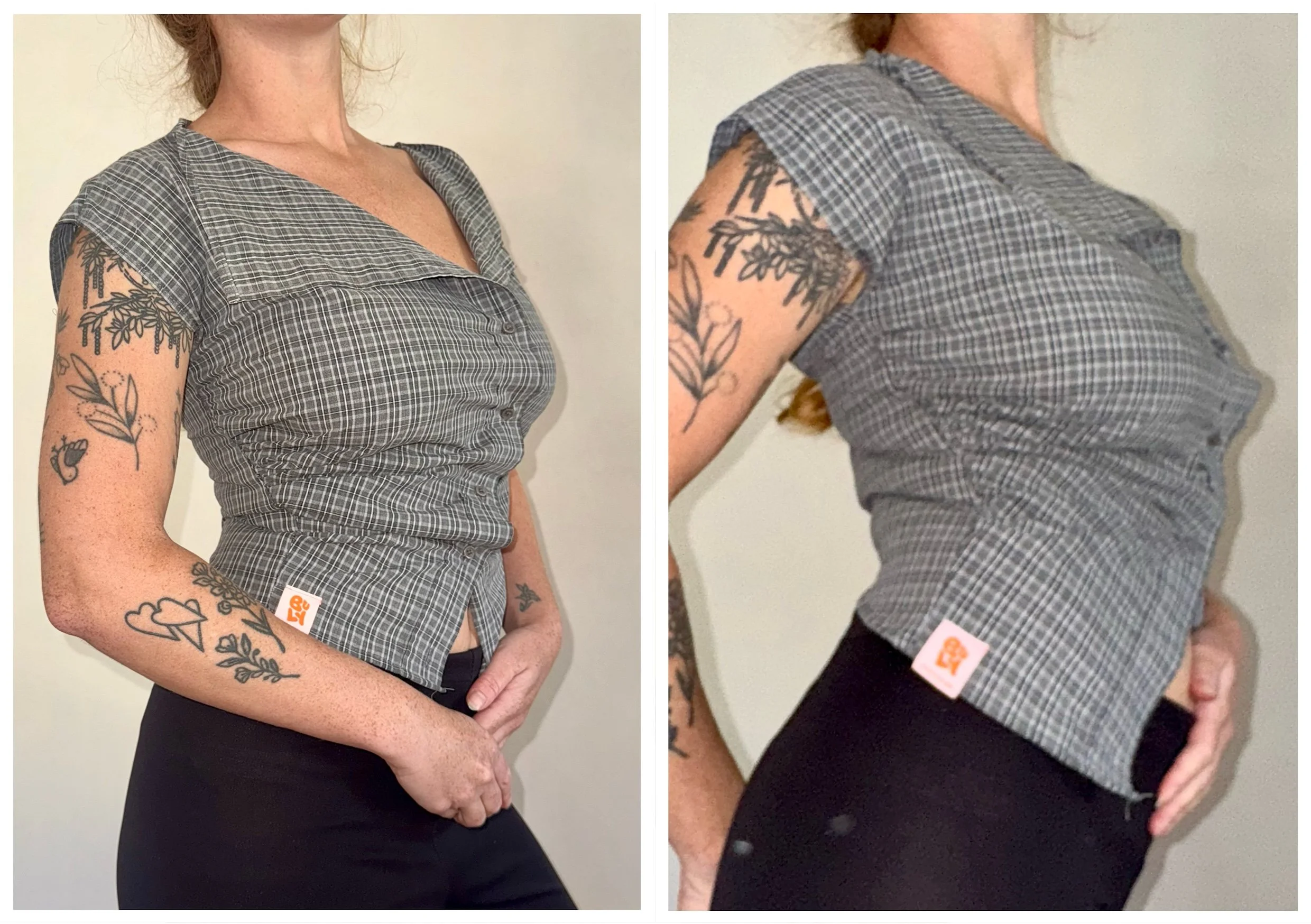 Une femme porte un haut à carreaux gris et noirs avec des manches courtes et un col en V. Elle a plusieurs tatouages sur ses bras, notamment des feuilles, une clé, et un nuage. Elle porte un pantalon noir