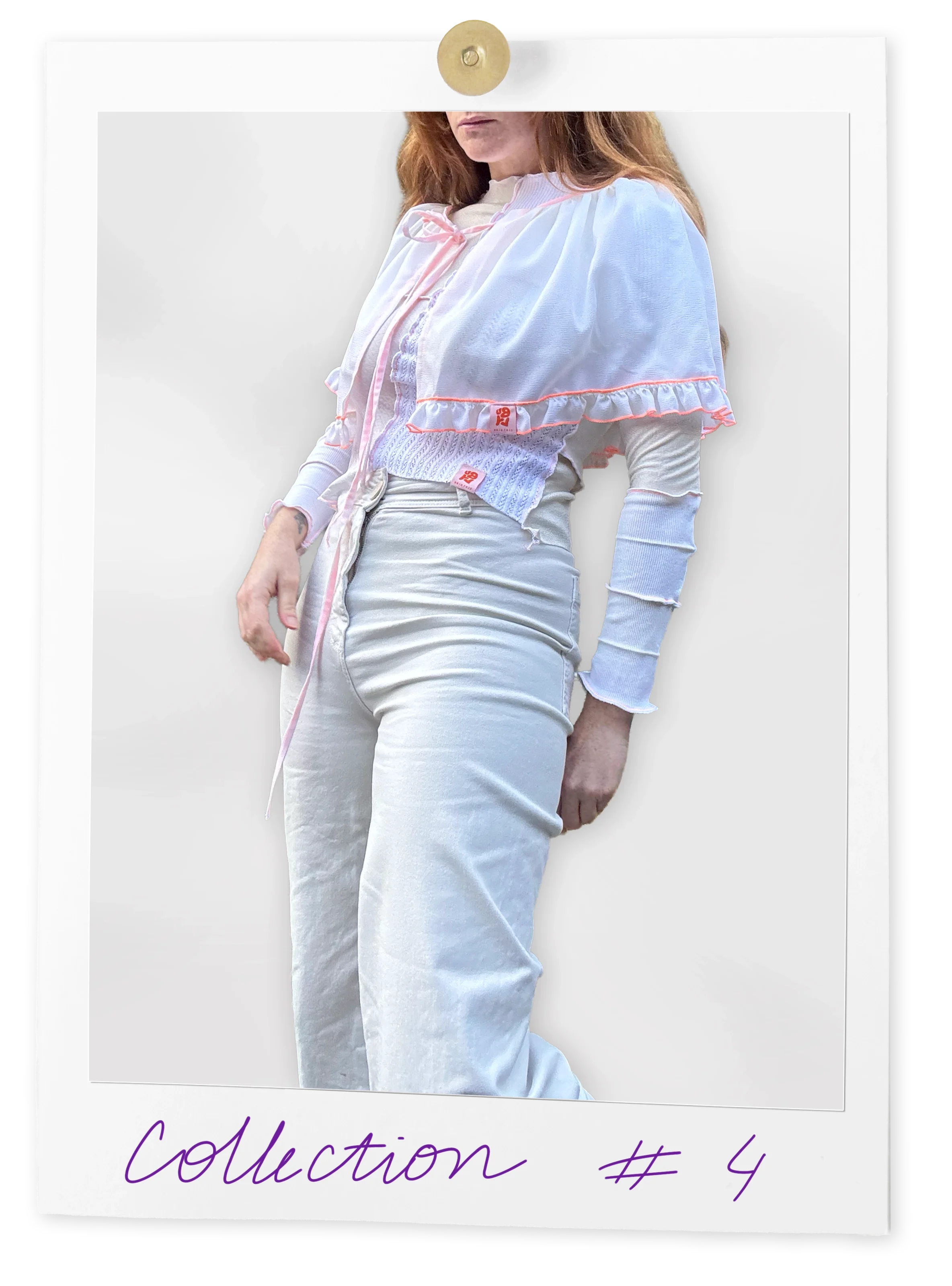 Une femme portant un haut blanc à manches longues, un veston transparent à bordures roses, et un pantalon beige, posant contre un mur blanc.