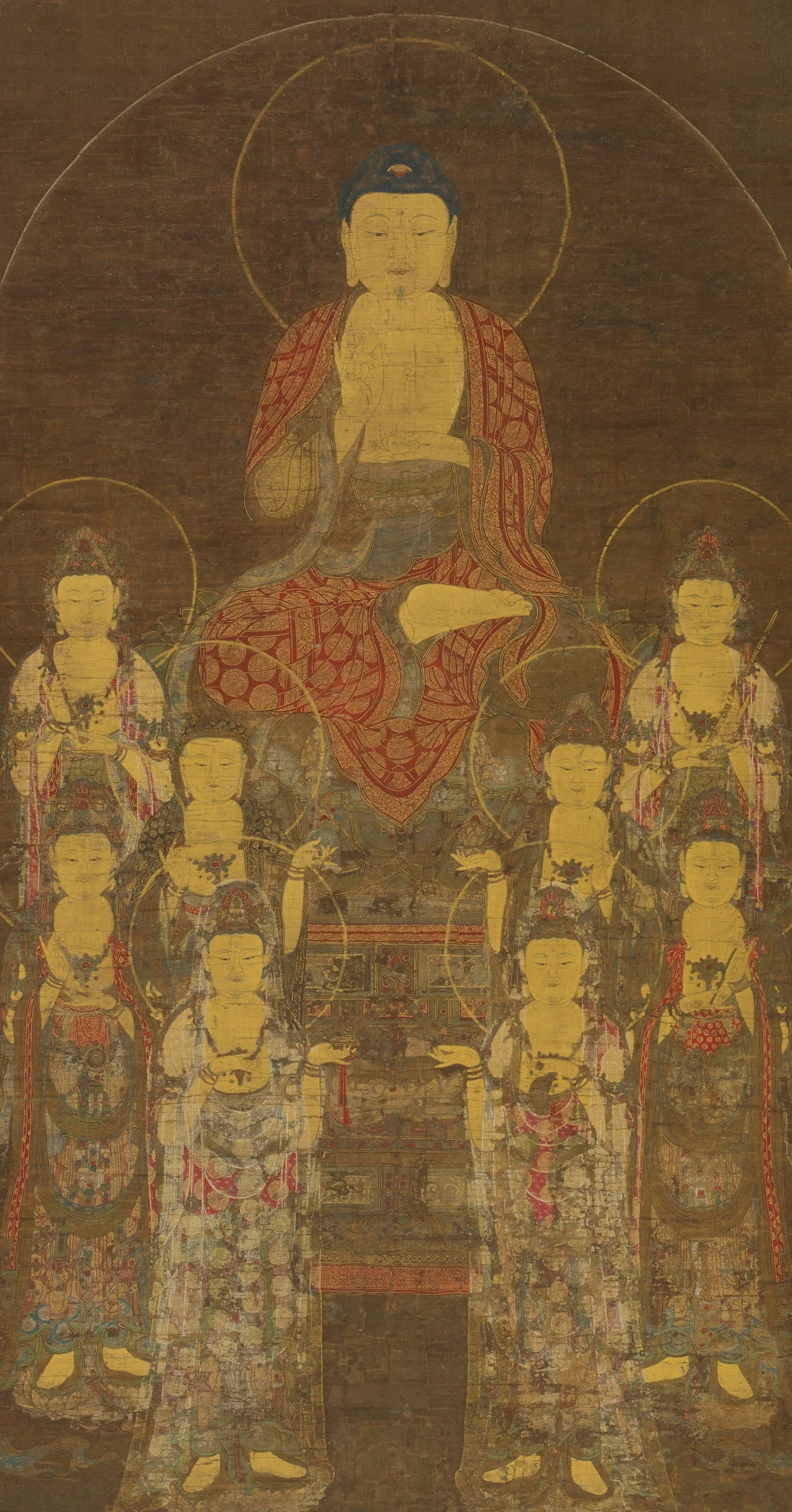 A traditional Buddhist thangka painting depicting a central figure surrounded by other deities. The central figure has a halo, is seated, and makes a hand gesture. The surrounding figures also have halos and are dressed in ornate robes and jewelry.