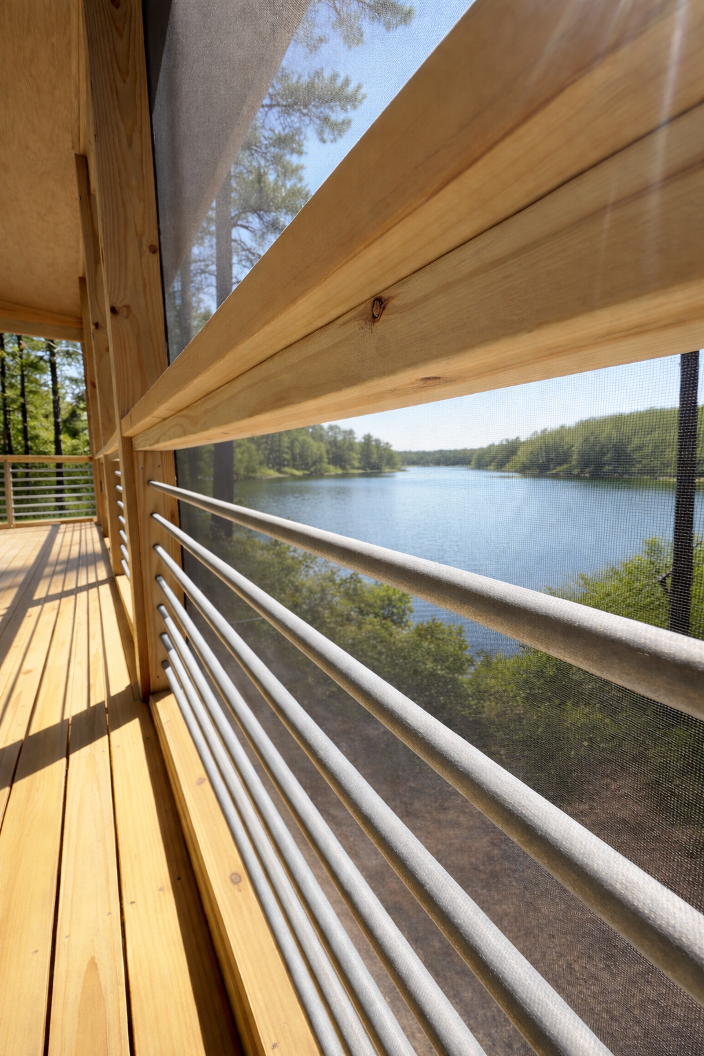 View through a screened balcony overlooking a river surrounded by trees on a sunny day.