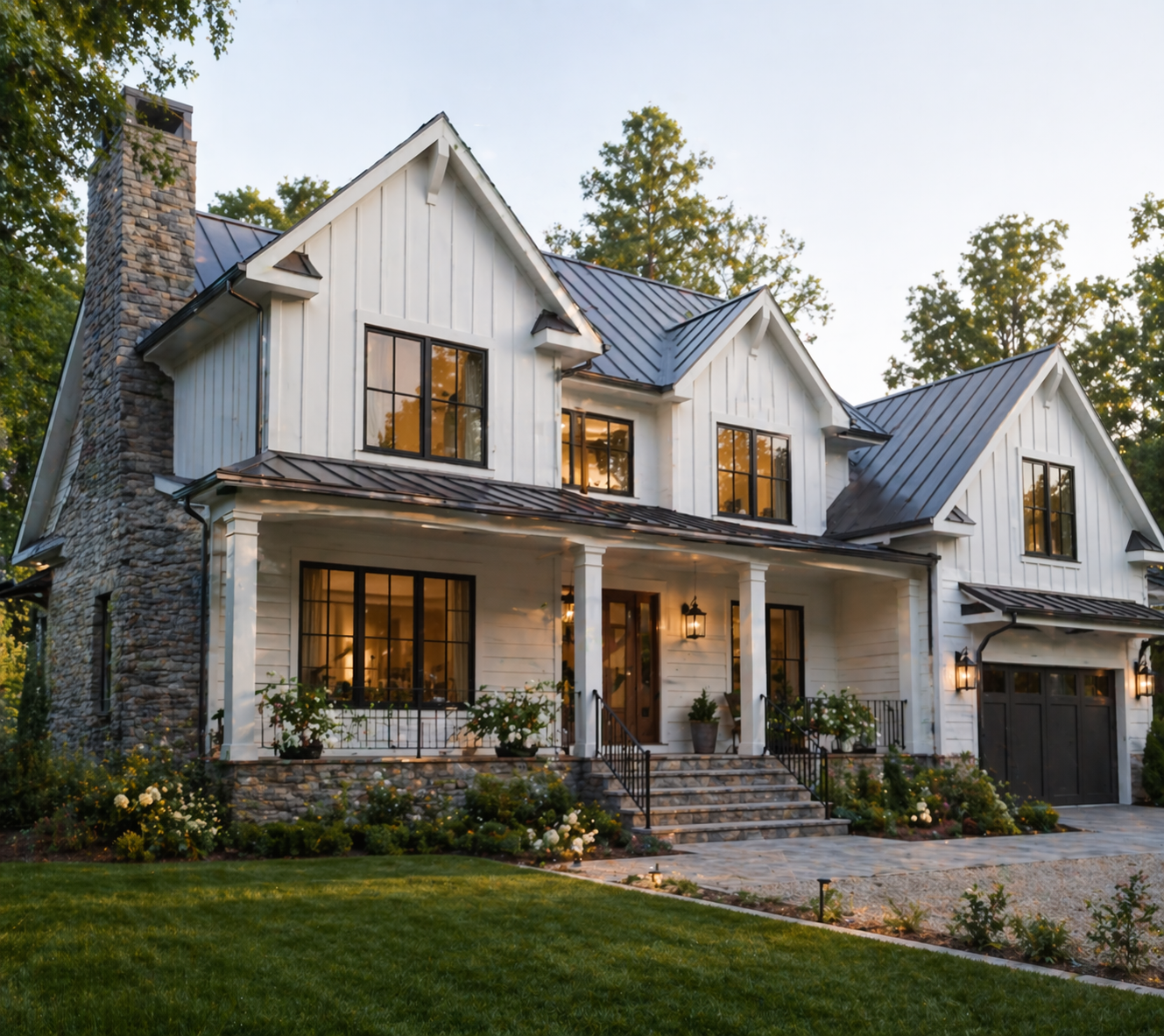A modern two-story house with white vertical siding, black window frames, a stone chimney, and a metal roof, surrounded by greenery and a landscaped garden and located in the Durham, Chapel Hill, or Carrboro area