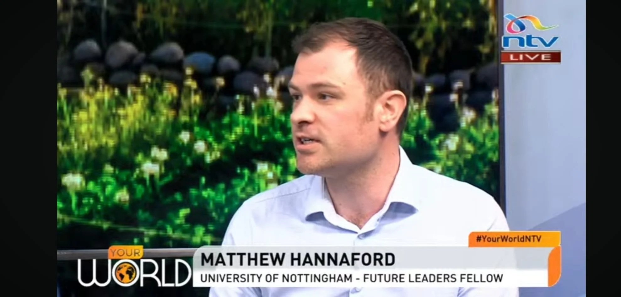 Television interview with a man named Matthew Hanneford from the University of Nottingham, identified as a future leader fellow, speaking on a news program called Your World NTV, with a background of green bushes and a screen displaying the NTV logo and hashtag #YourWorldNTV.