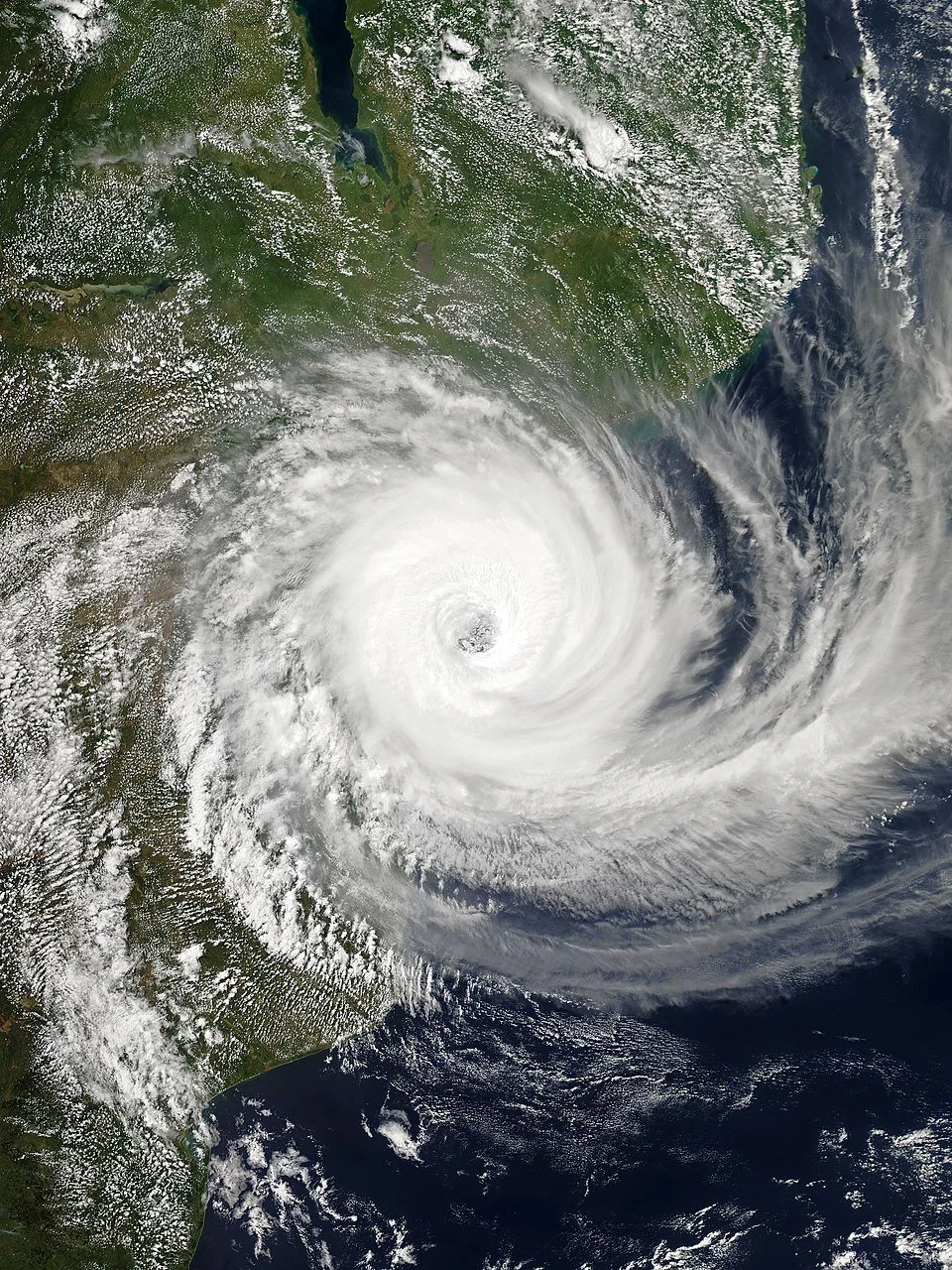 Satellite image of a hurricane with a clear eye over land and ocean.