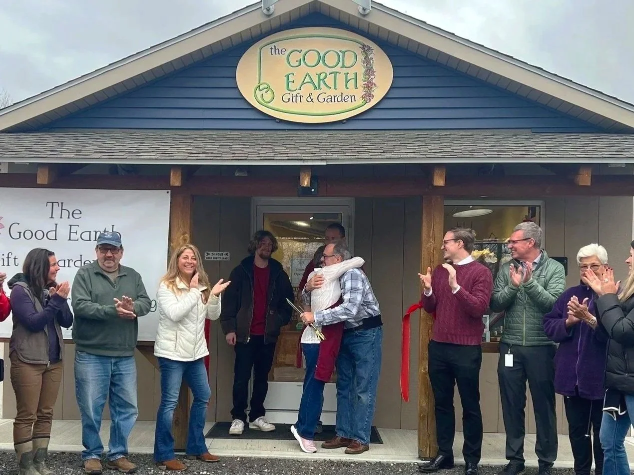 Group of people celebrating outside a shop called The Good Earth Gift & Garden with a ribbon cutting ceremony.