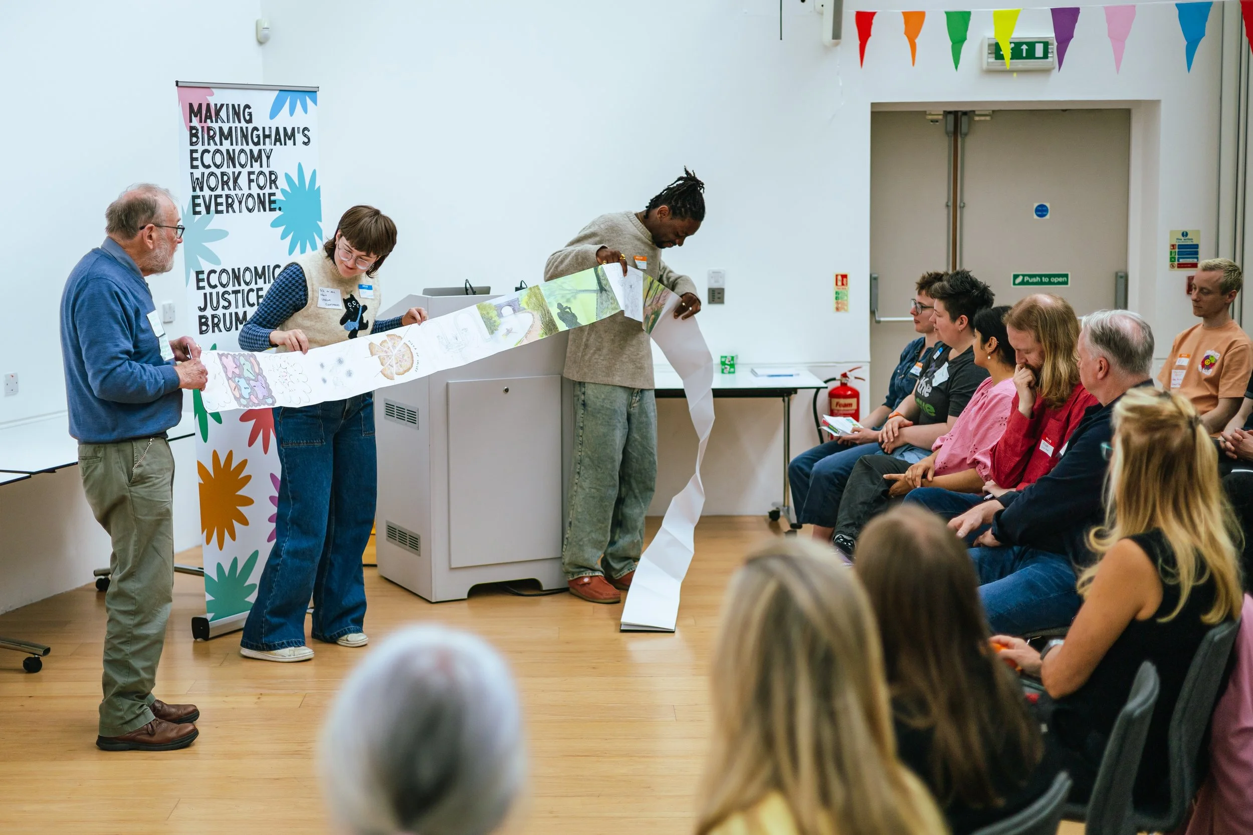 Economic Justice Huddles Showcase - A man shows off his art journal with his peers