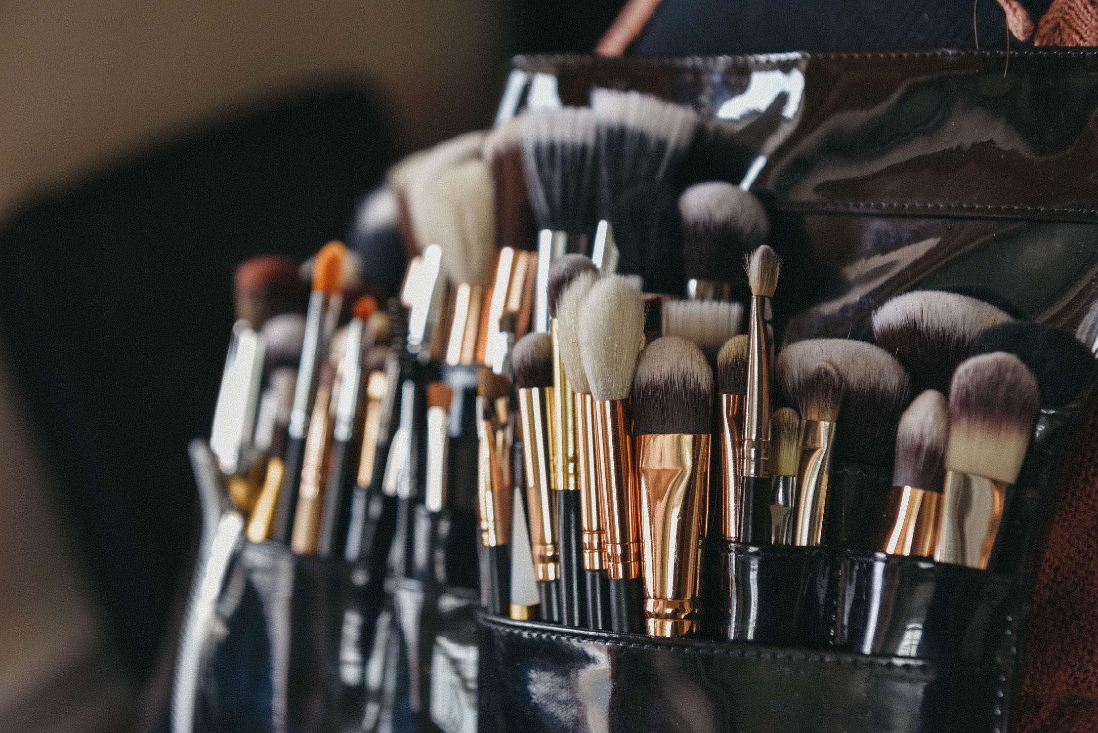 Close-up of a set of various makeup brushes inside a black makeup brush holder.