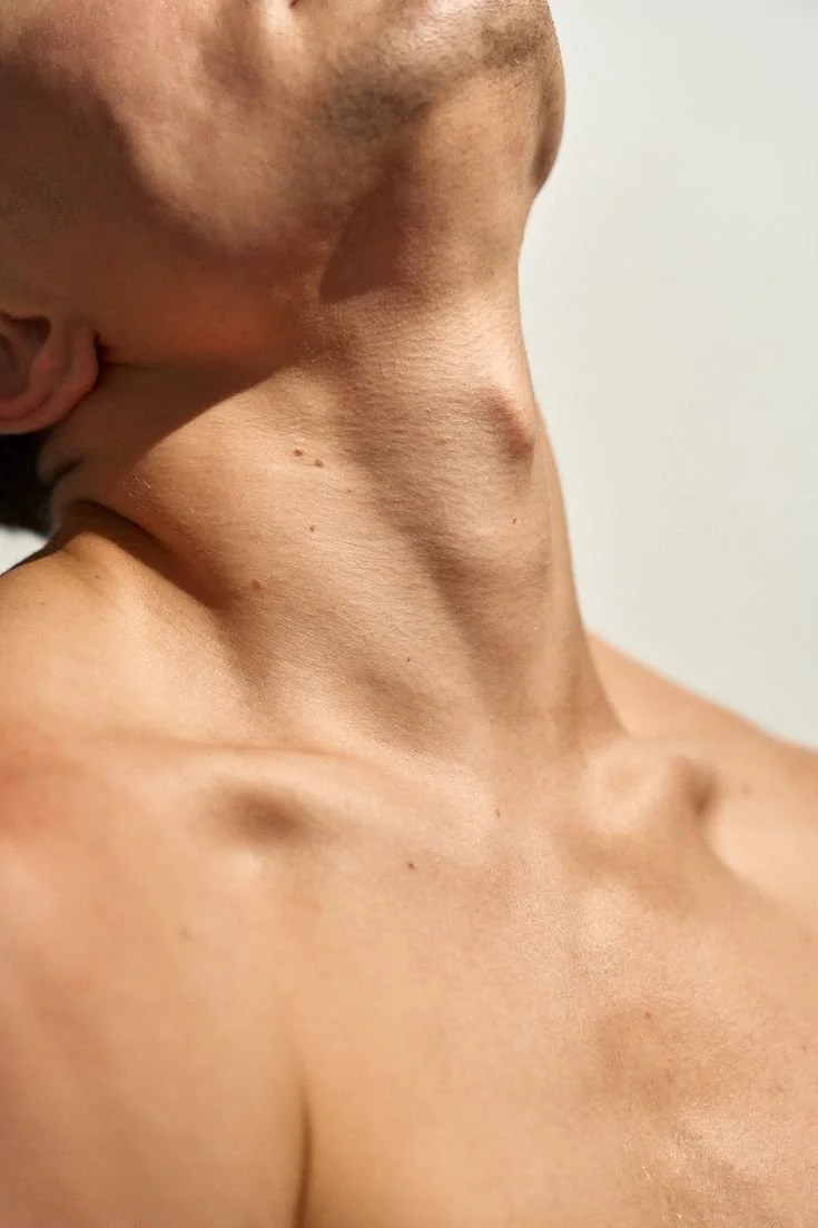 Gros plan du cou et de la clavicule d'une personne nue, mettant en évidence la peau et les détails anatomiques.
