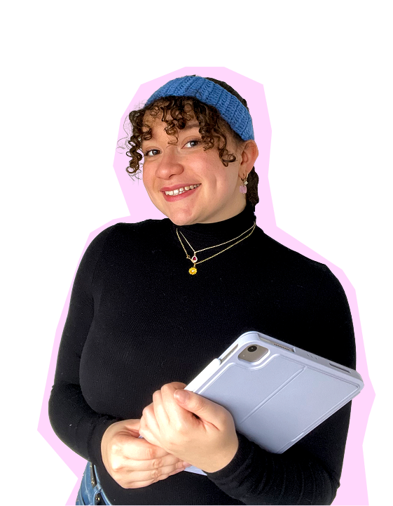 Une femme souriante avec un bandeau bleu, portant un pull noir et des colliers, tient une tablette en main, arrière-plan rose clair.