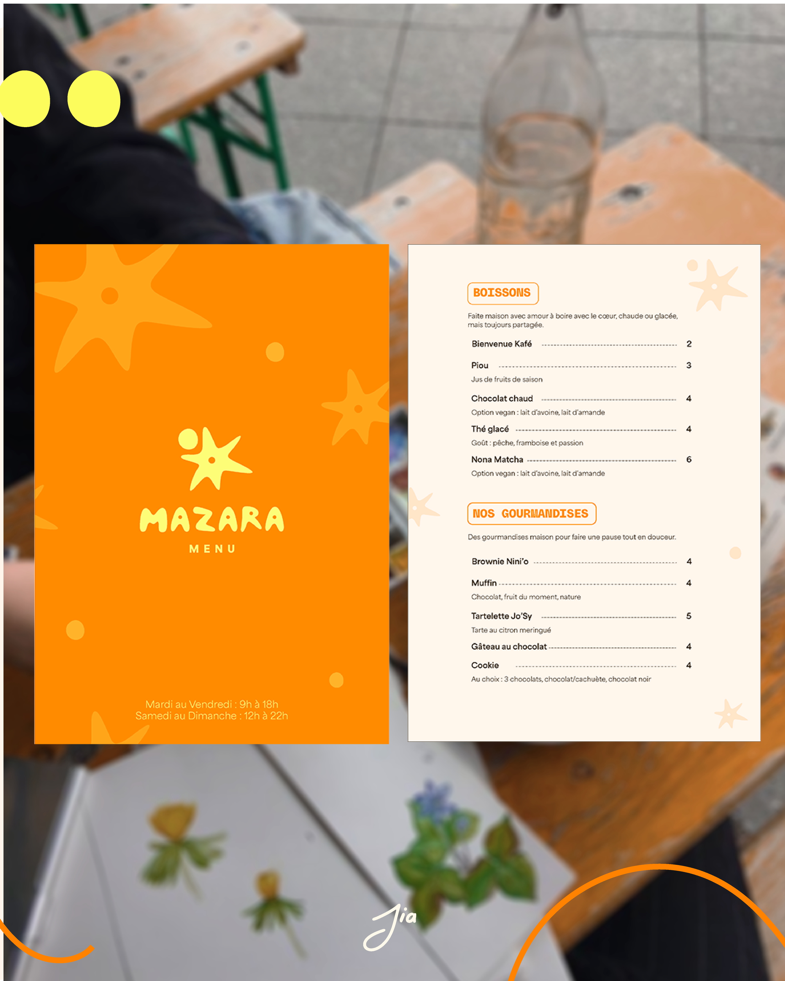 Menu de restaurant Mazara avec sections pour boissons et gourmandises, fond orange avec des étoiles jaunes, et détails d'ouverture. En arrière-plan, une table en bois avec un plateau blanc, des fleurs, et une bouteille d'eau.