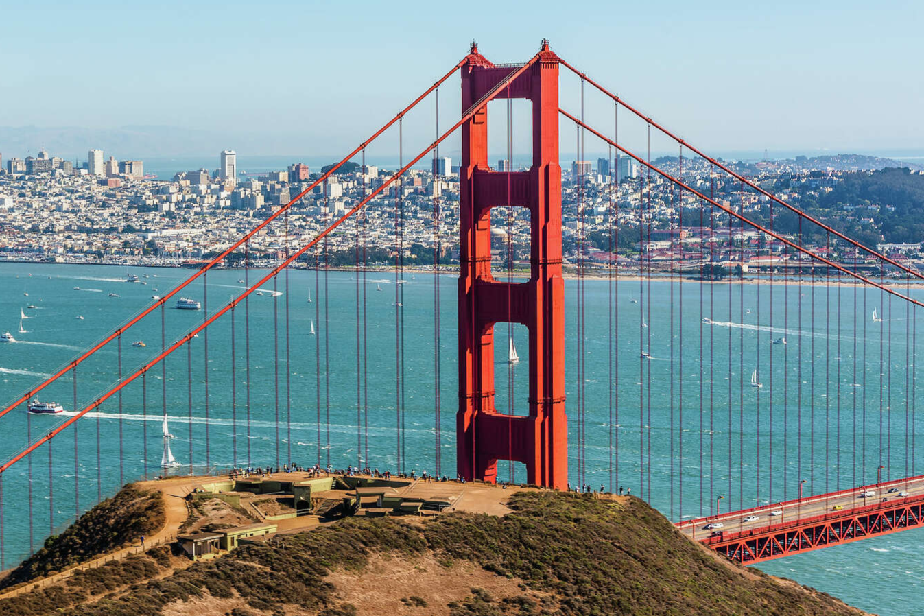 Golden Gate Bridge in San Francisco with boats on the water and city skyline in the background.