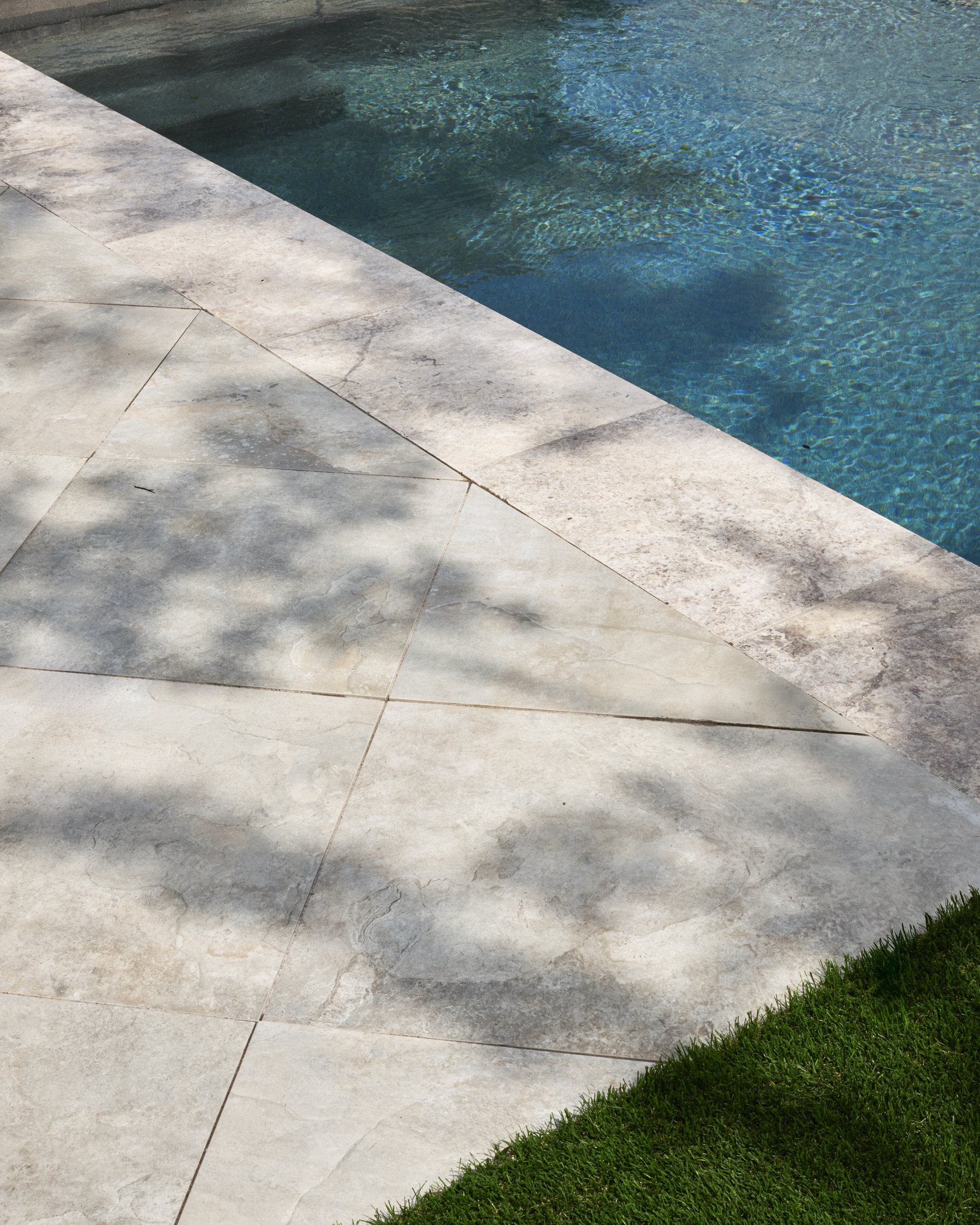 Backyard hardscape and landscape renovation complete with Porcelain Pavers, Belgard retaining walls, and evergreen planting design in North Dallas  | Designed by Caroline Higgins Design in Dallas, TX