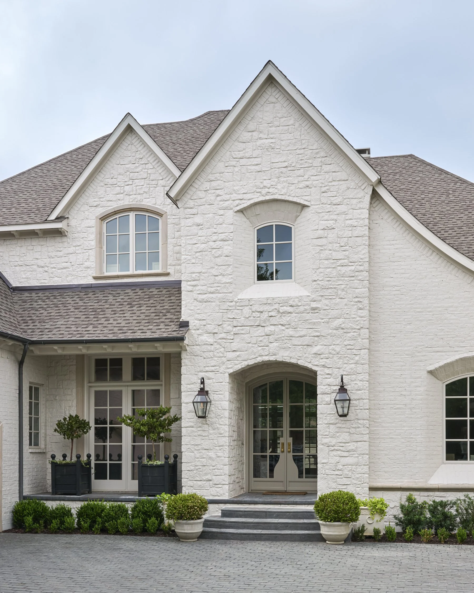 French-inspired front yard and motor courtyard landscape design with layered evergreen shrubs in the Park Cities  | Designed by Caroline Higgins Design in Dallas, TX