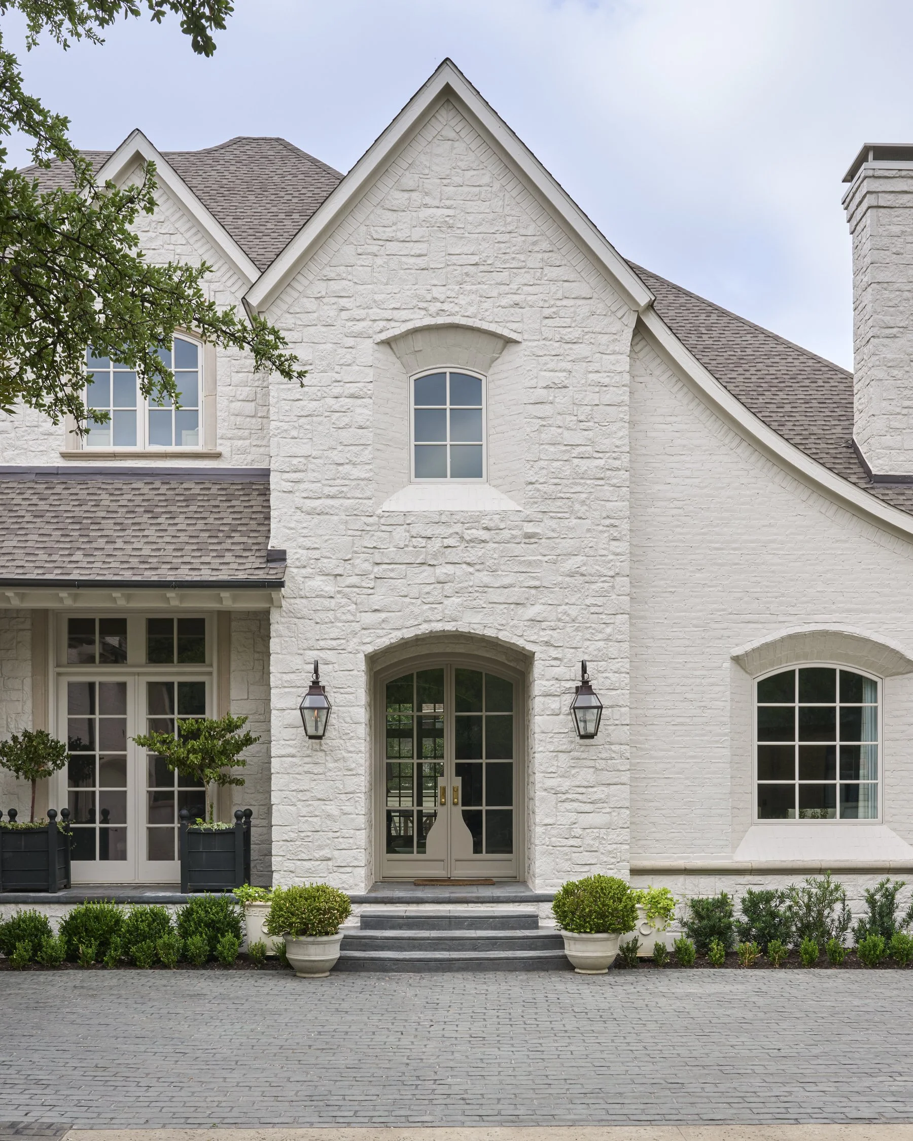 French-inspired front yard and motor courtyard landscape design with layered evergreen shrubs in the Park Cities  | Designed by Caroline Higgins Design in Dallas, TX