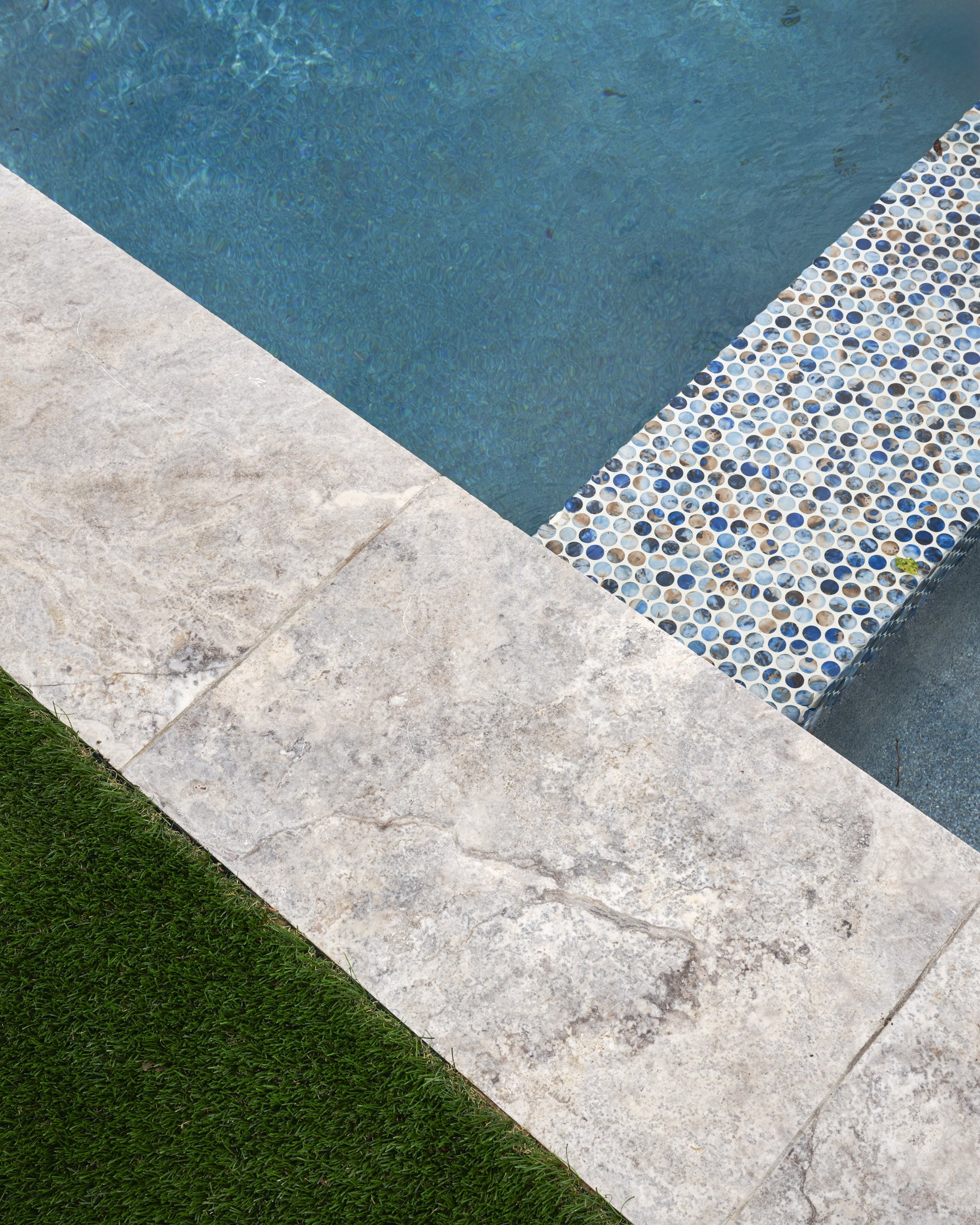 Backyard hardscape and landscape renovation complete with Porcelain Pavers, Belgard retaining walls, and evergreen planting design in North Dallas  | Designed by Caroline Higgins Design in Dallas, TX