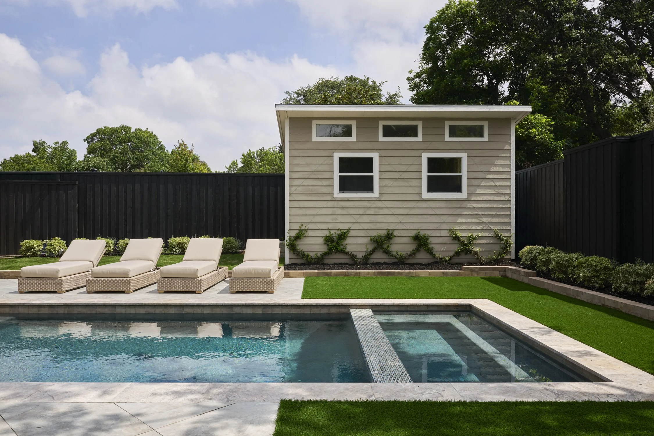 Backyard hardscape and landscape renovation complete with Porcelain Pavers, Belgard retaining walls, and evergreen planting design in North Dallas  | Designed by Caroline Higgins Design in Dallas, TX