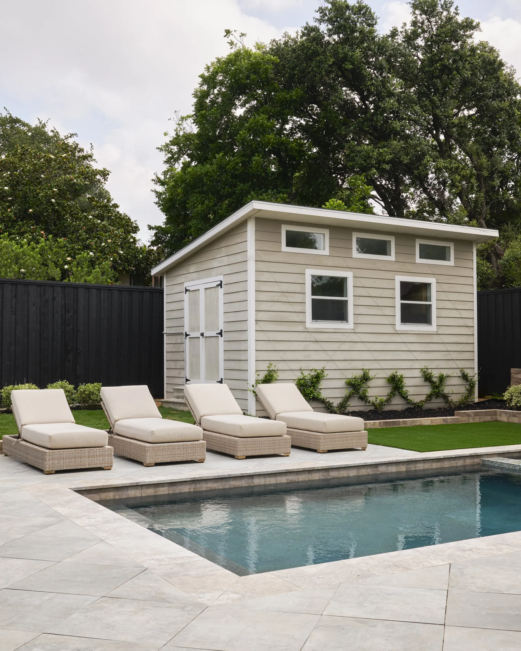 Backyard hardscape and landscape renovation complete with Porcelain Pavers, Belgard retaining walls, and evergreen planting design in North Dallas  | Designed by Caroline Higgins Design in Dallas, TX