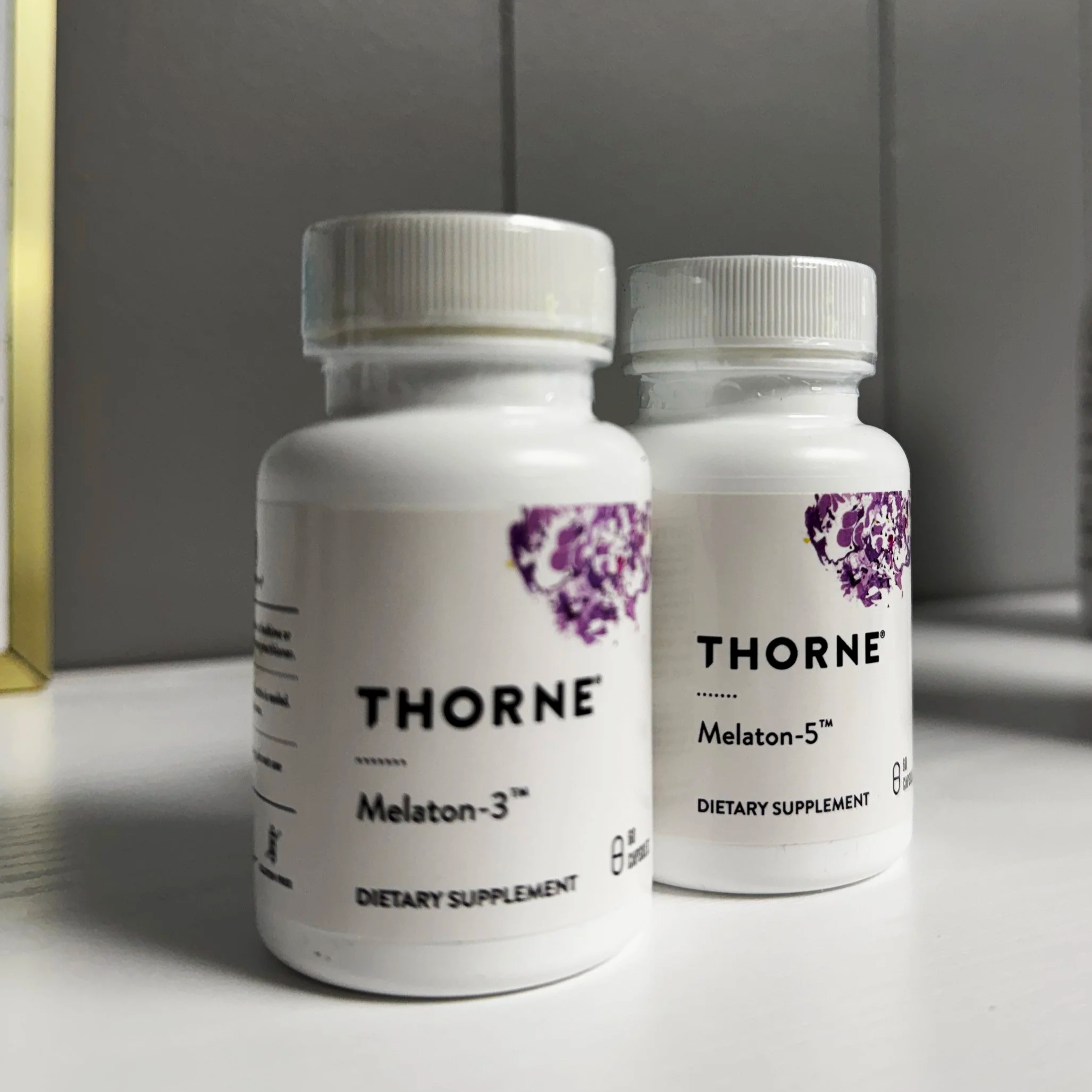 Close-up of supplement bottles labeled 'Thorne Melatonin-3' and 'Thorne Melatonin-5' on a shelf.