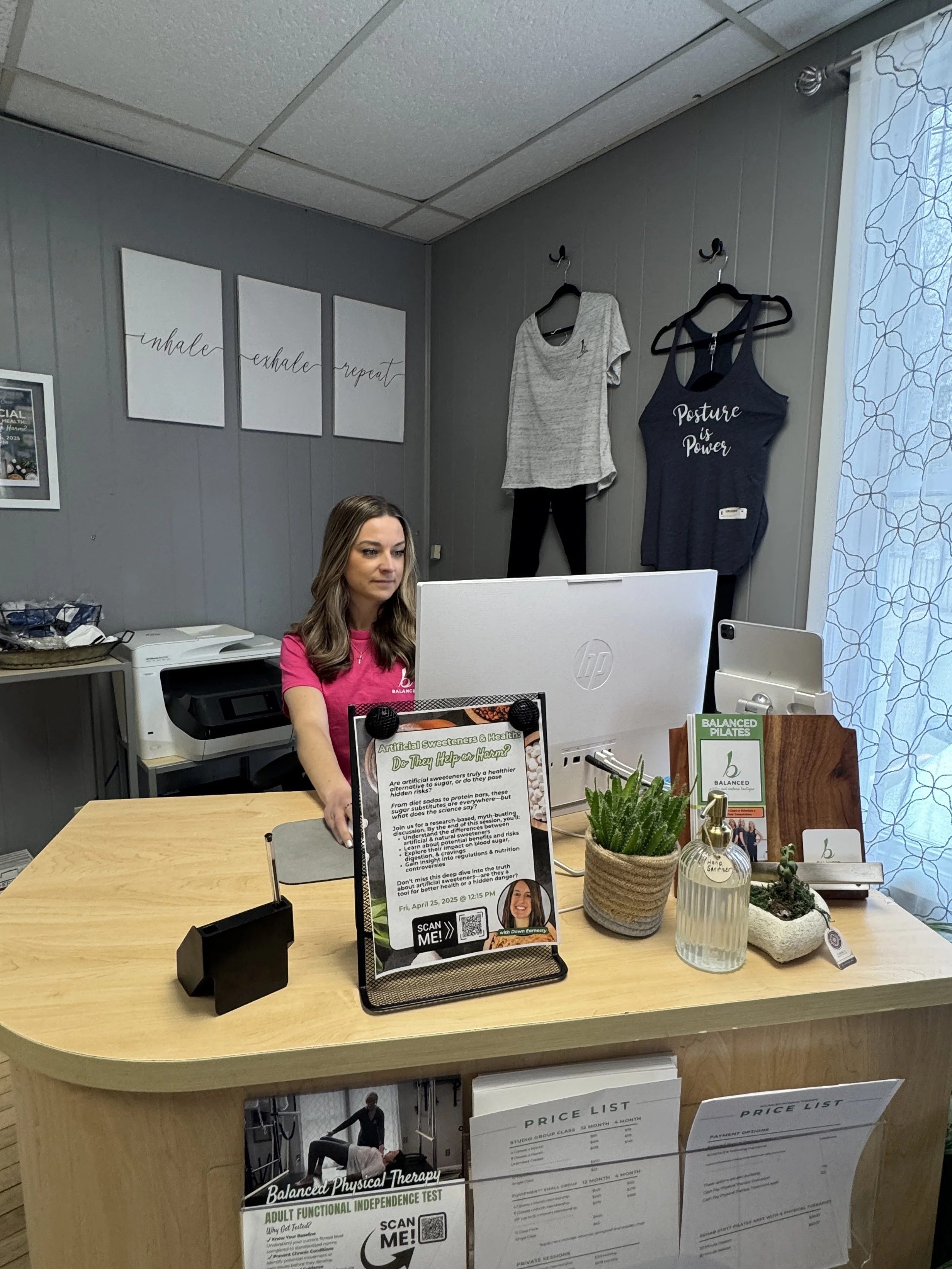 A woman sitting at a reception desk at Balanced Pilates and Wellness Boutique in Midland, Michigan.