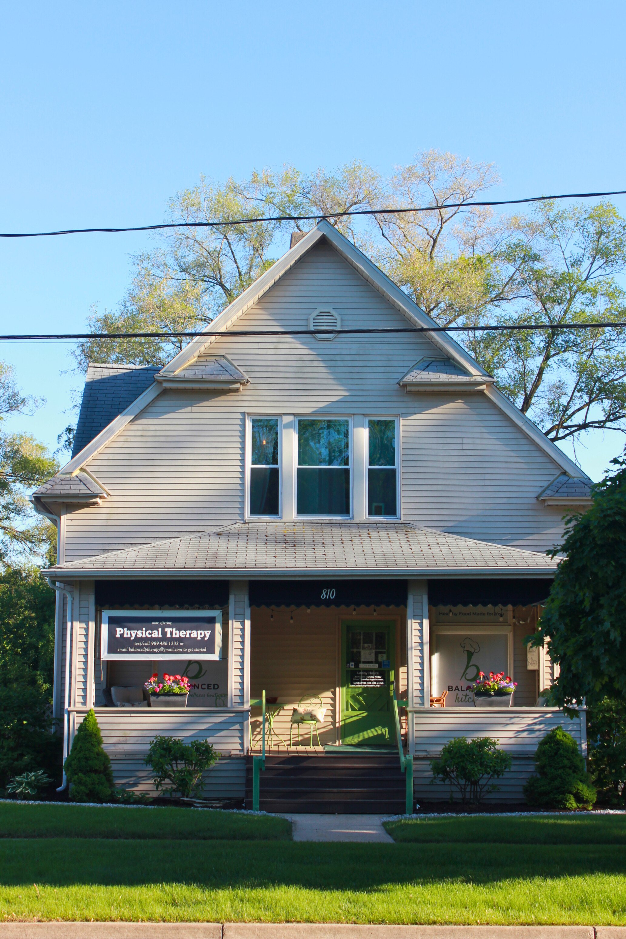 A two-story house with a front porch, a gable roof, and a sign advertising physical therapy services. The house is at Balanced Pilates and Wellness Boutique in Midland, Michigan.