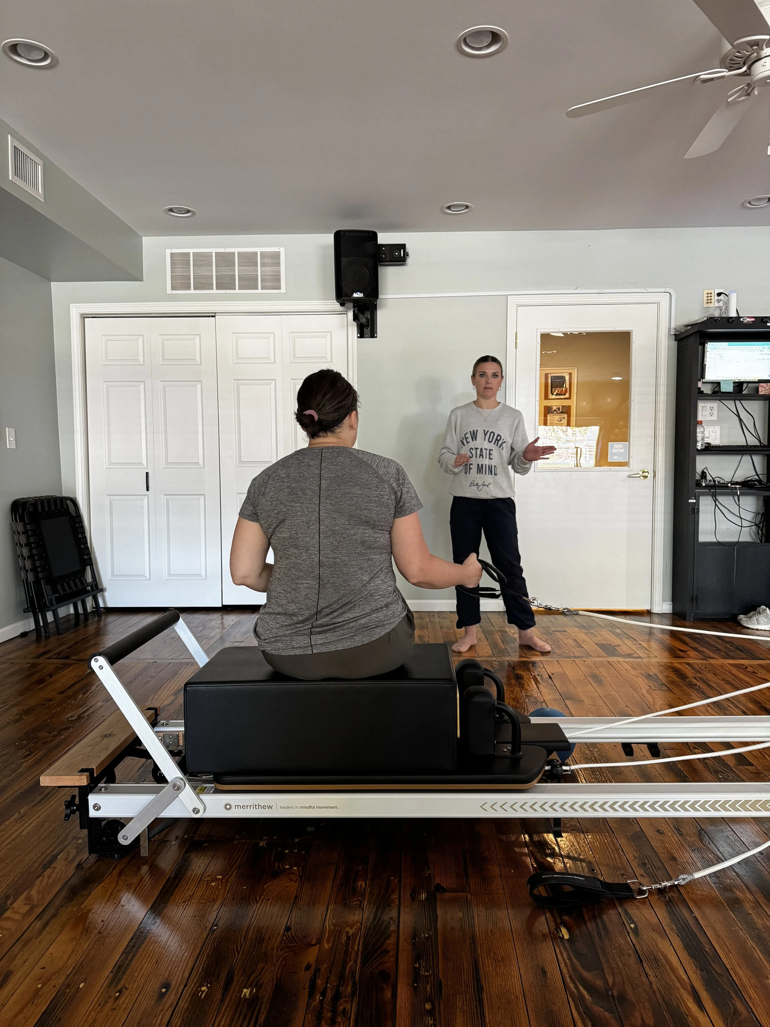 A woman with sitting on a reformer in Balanced Pilates and Wellness Boutique in Midland, Michigan.