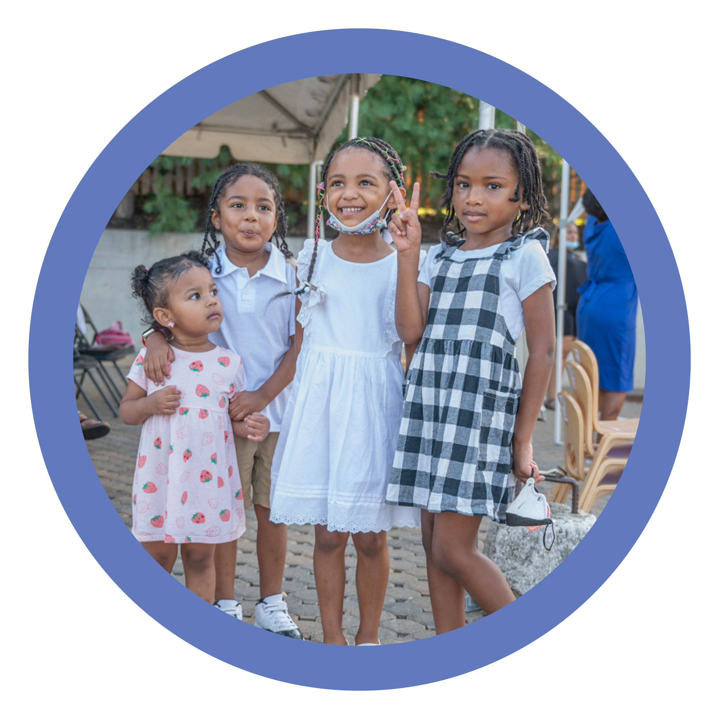 Four young girls of diverse backgrounds standing together outdoors, smiling and posing for the camera during a gathering.