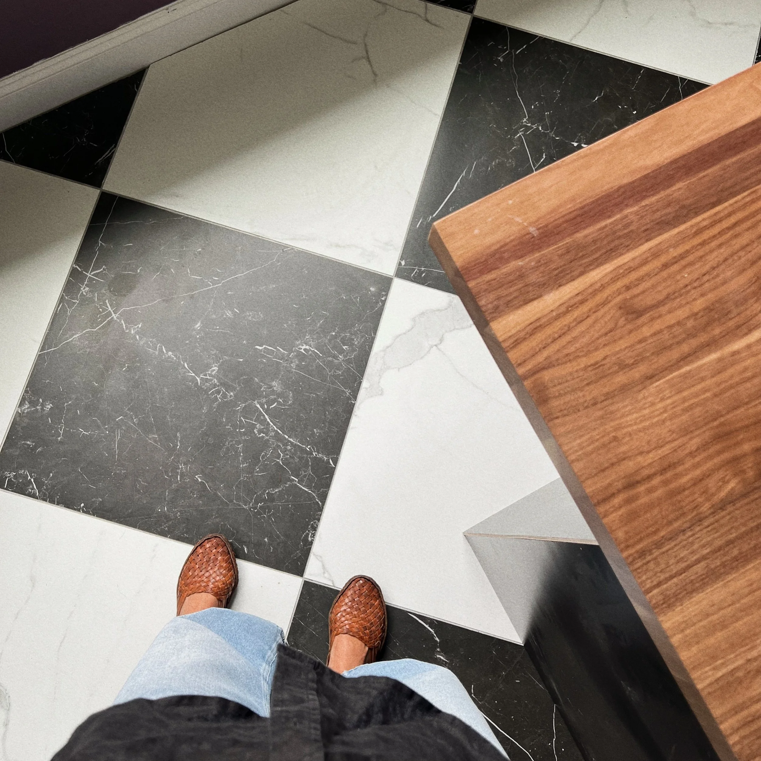 Interior designer selecting black and white marble-look floor tile with walnut cabinetry during a luxury kitchen design project in Jacksonville, Florida.