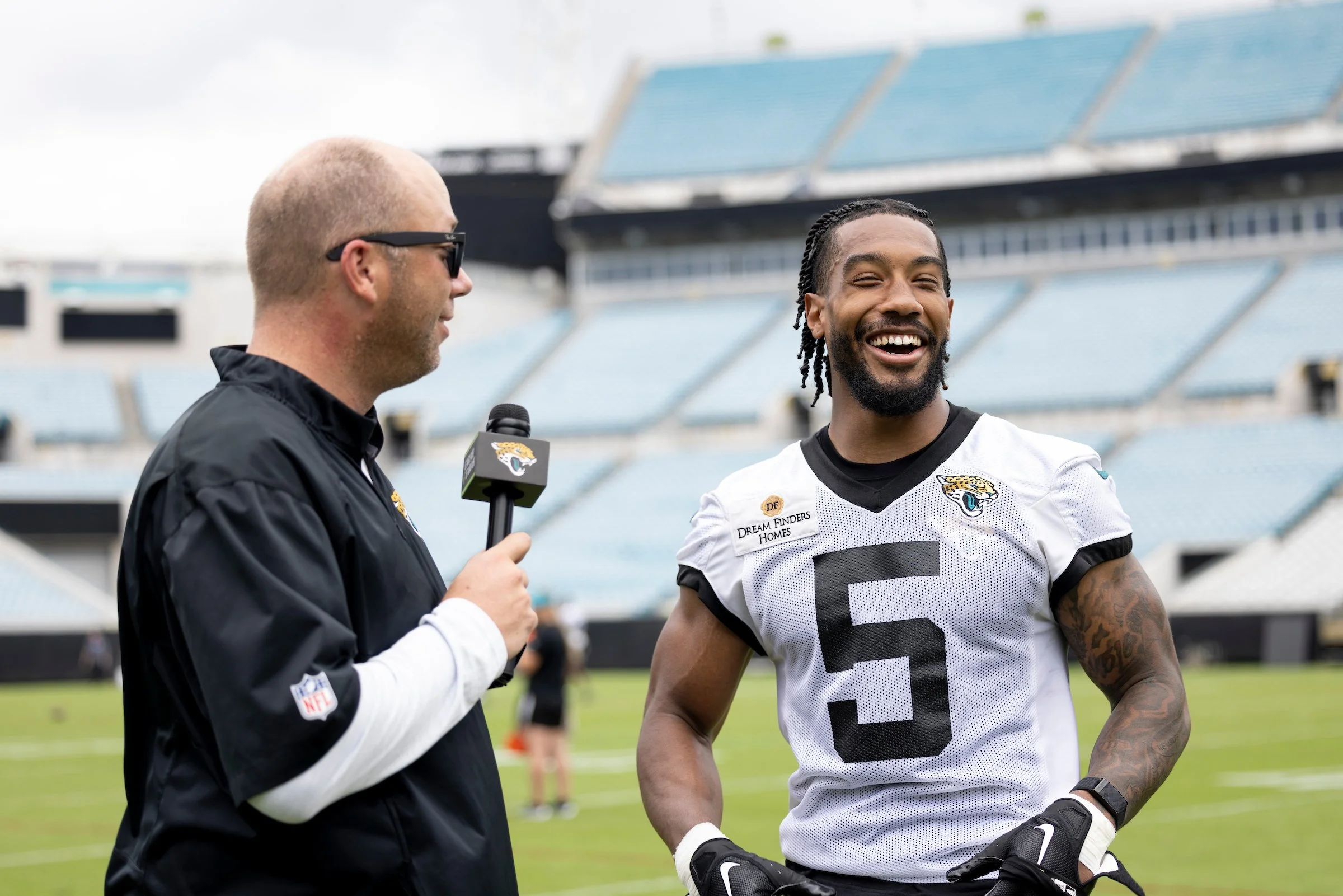 A football player from the Jacksonville Jaguars being interviewed by a reporter at a stadium.
