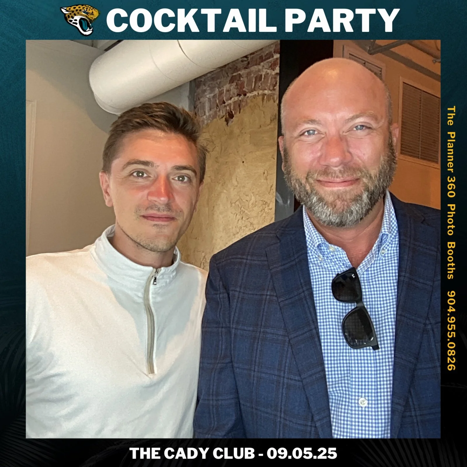 Two men standing side by side at a cocktail party, with the man on the right wearing sunglasses and a checkered shirt beneath a blazer. The background features brick and drywall walls.