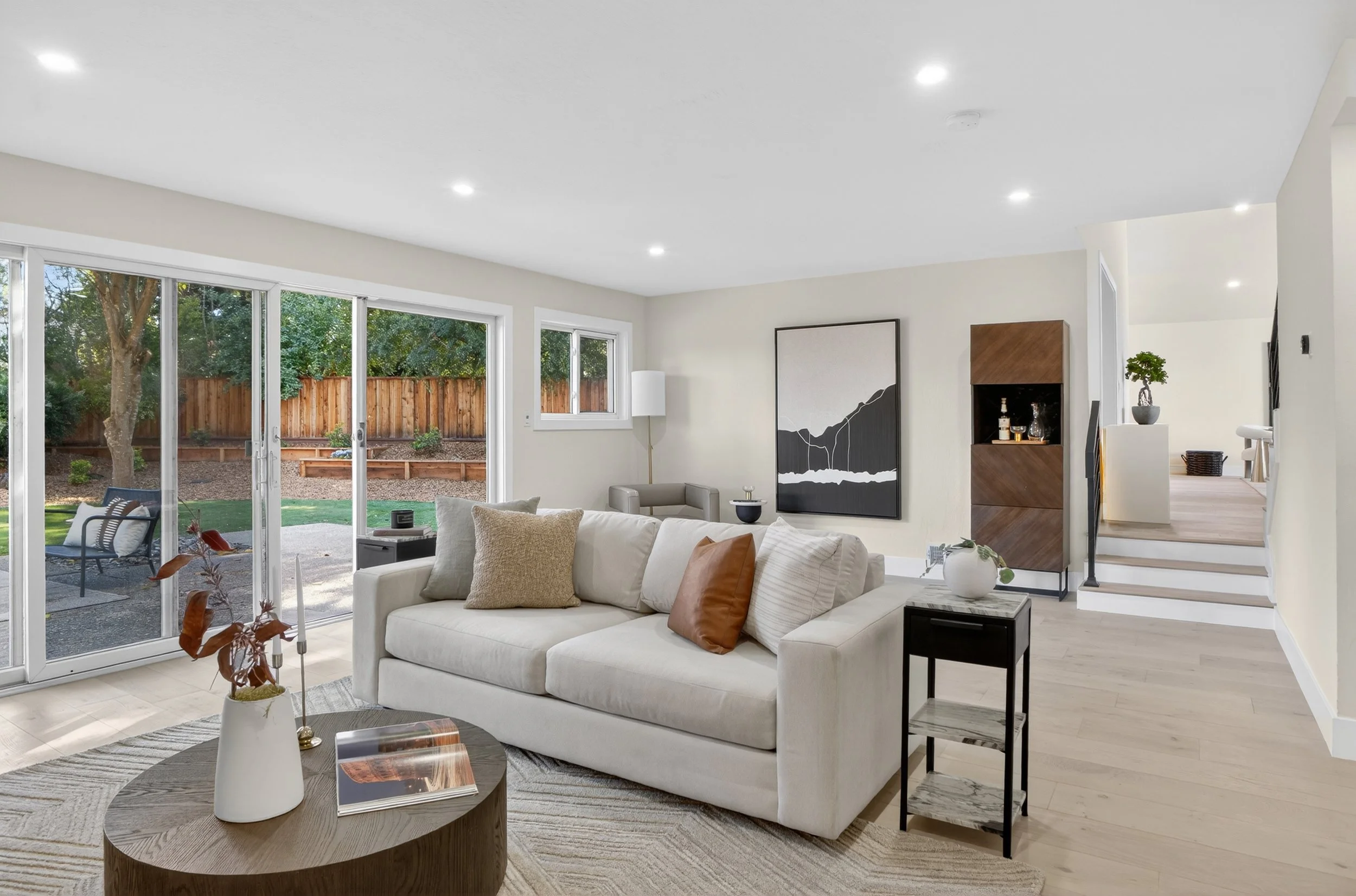 Living room with beige couch, decorative pillows, glass sliding door, and backyard view.